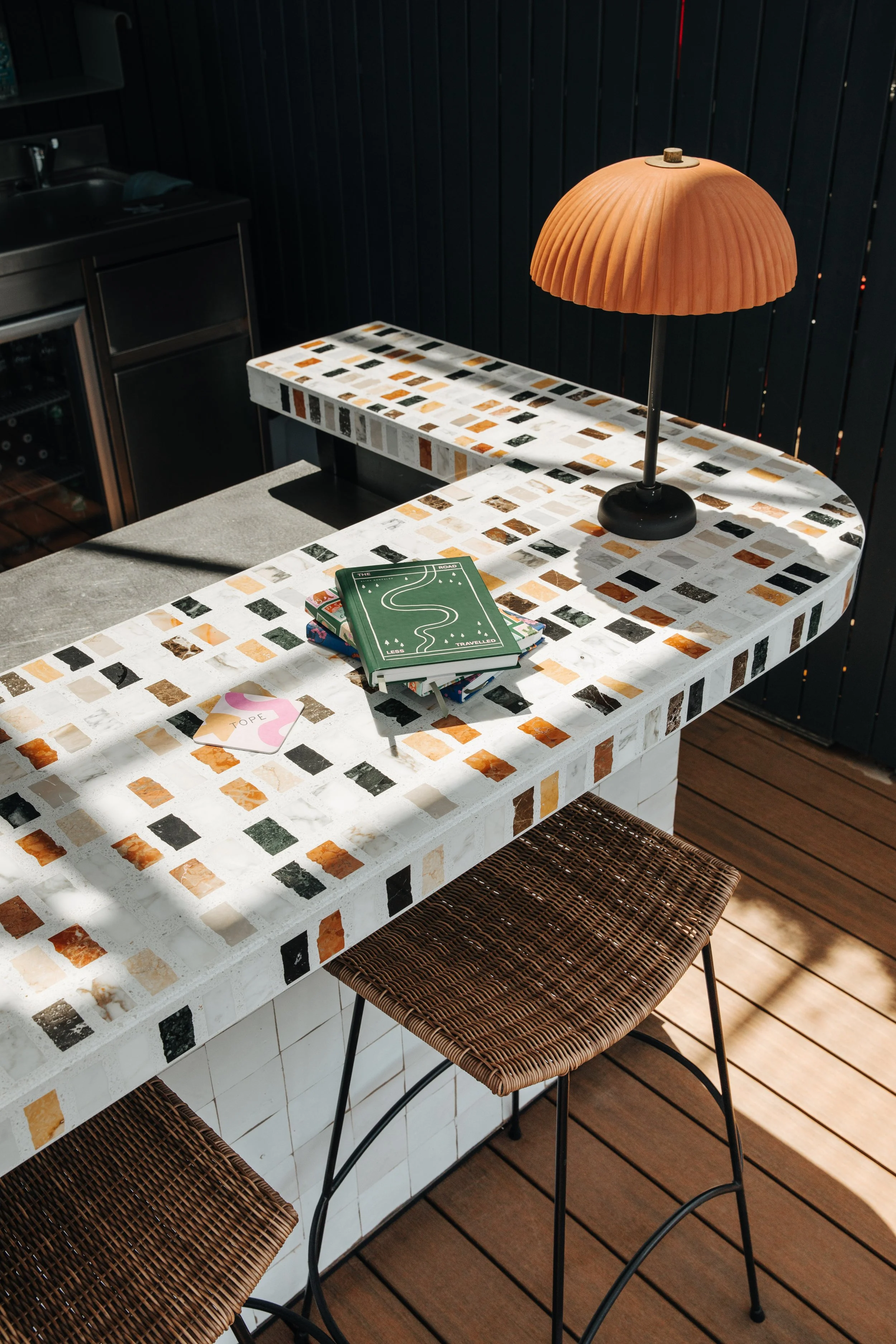 A mosaic countertop with a lamp, a small stack of books, and a pink heart-shaped note with the word 'hope' on it.