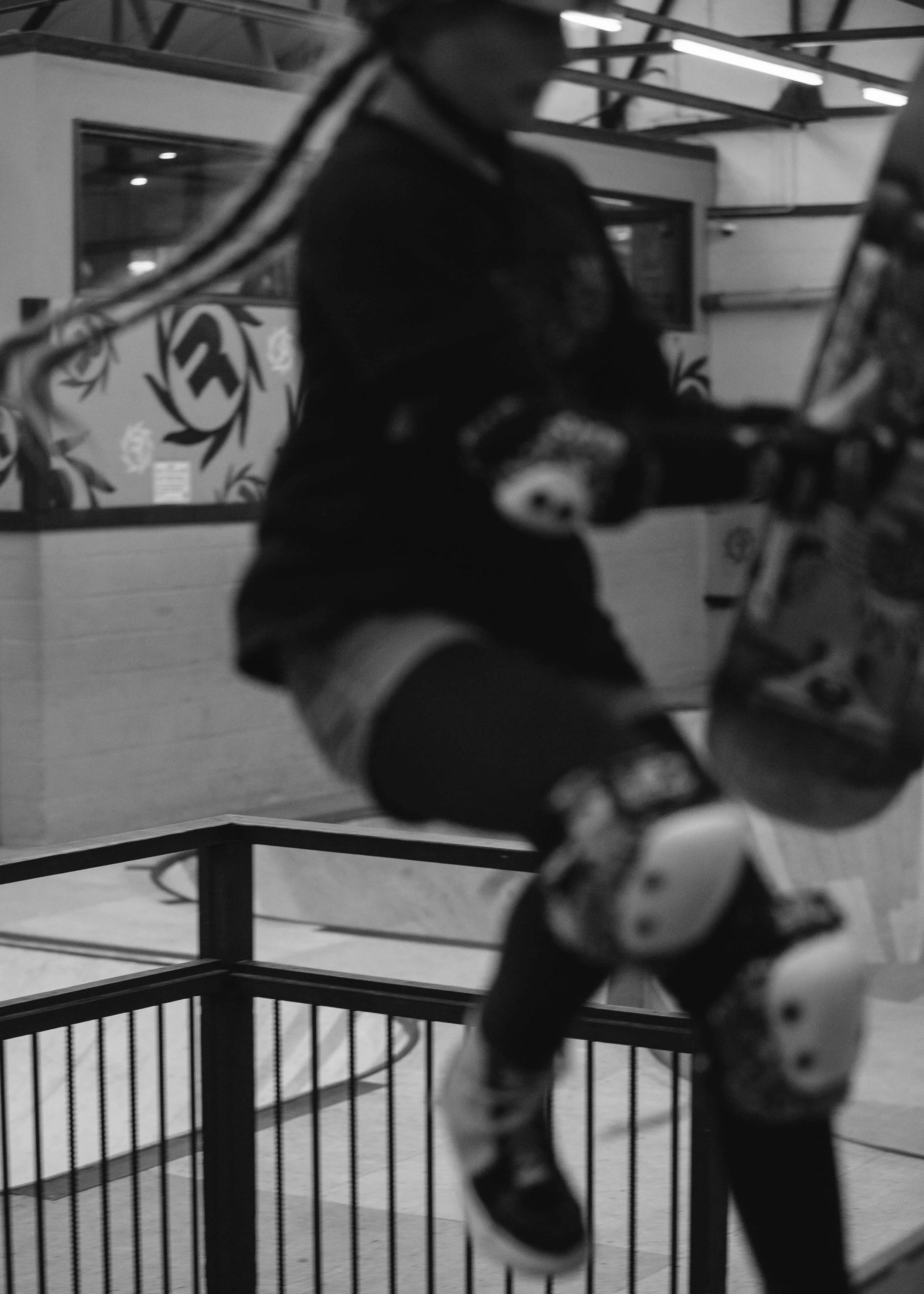A young boy in hockey gear, including helmet, shoulder pads, and skates, holding a hockey stick and puck, standing inside an ice rink or sports facility.