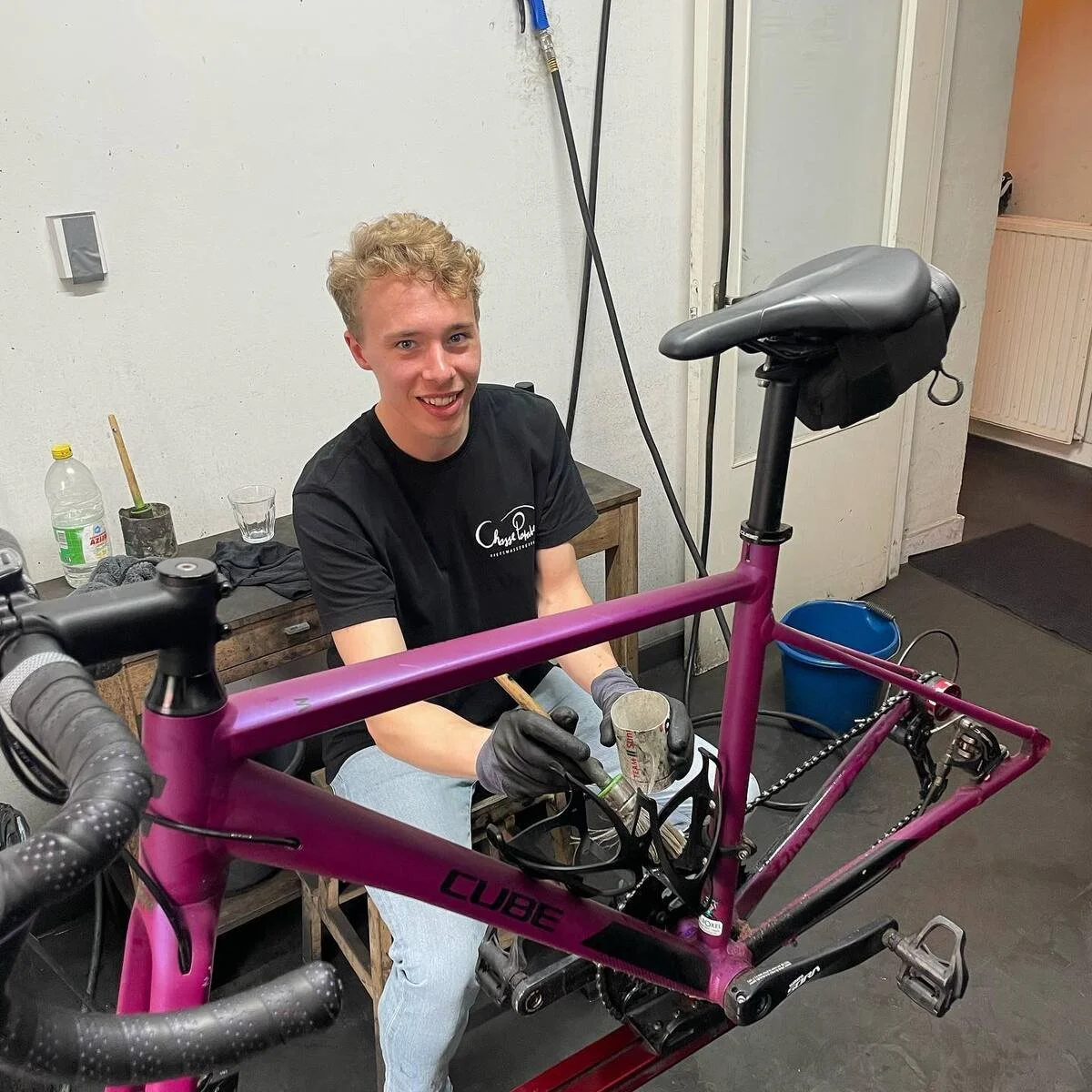 Bike mechanic washing a purple Cube road bike at Chasse Patate