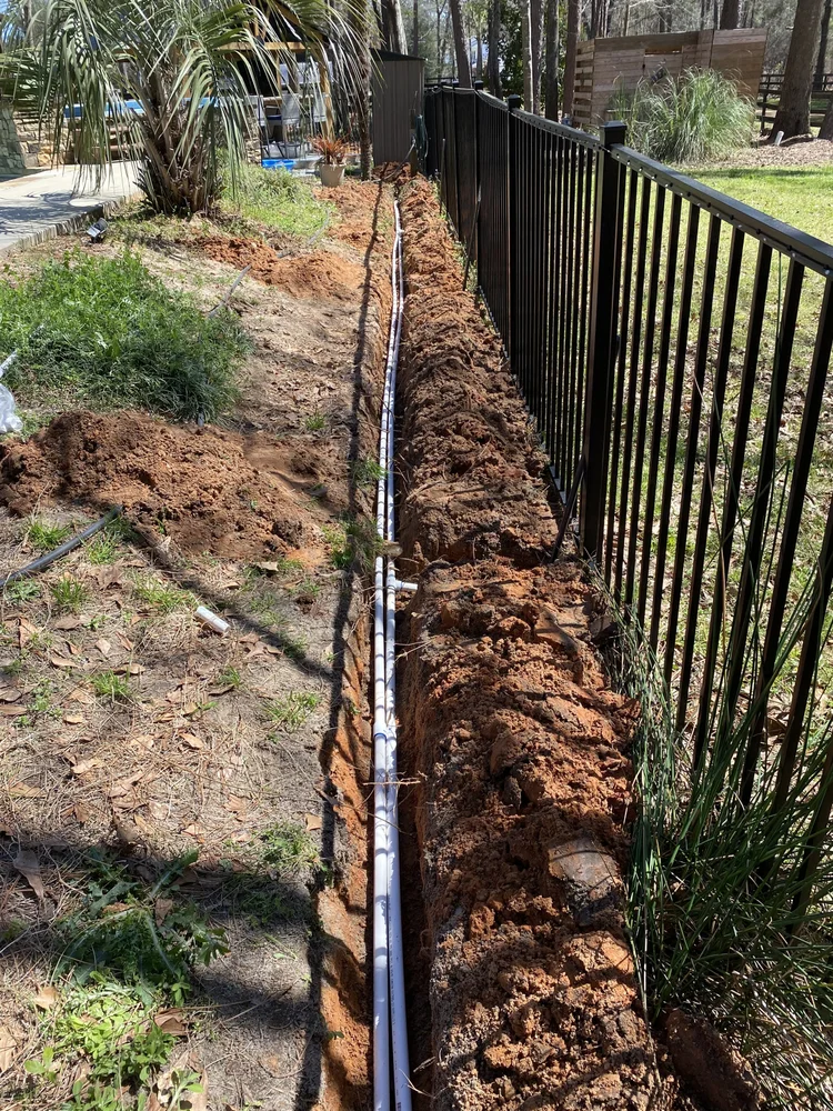 Irrigation pipe in a trench beside a fence