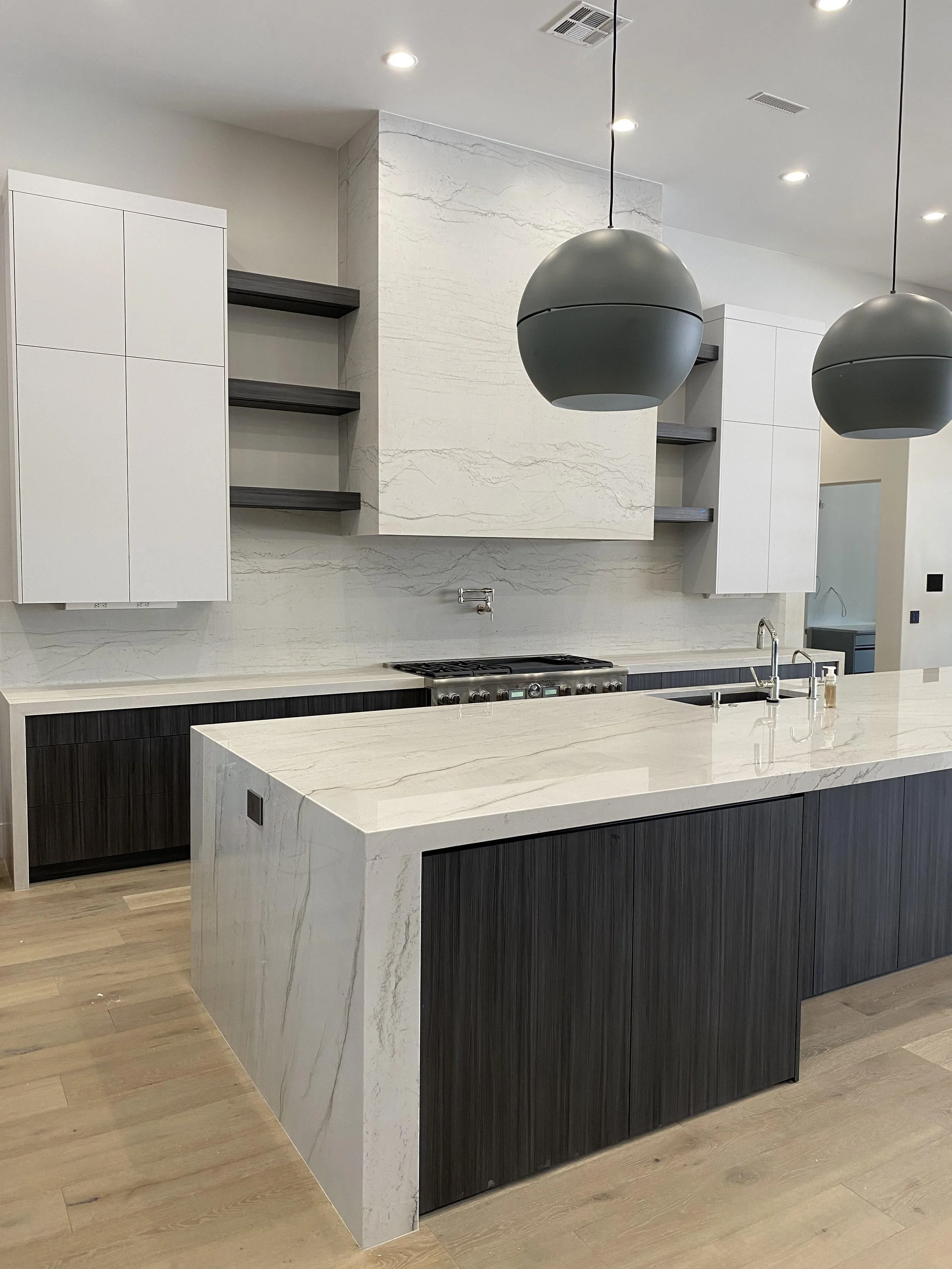 Kitchen and hood with quartzite countertops. Mitered edges, waterfall legs and full backsplash