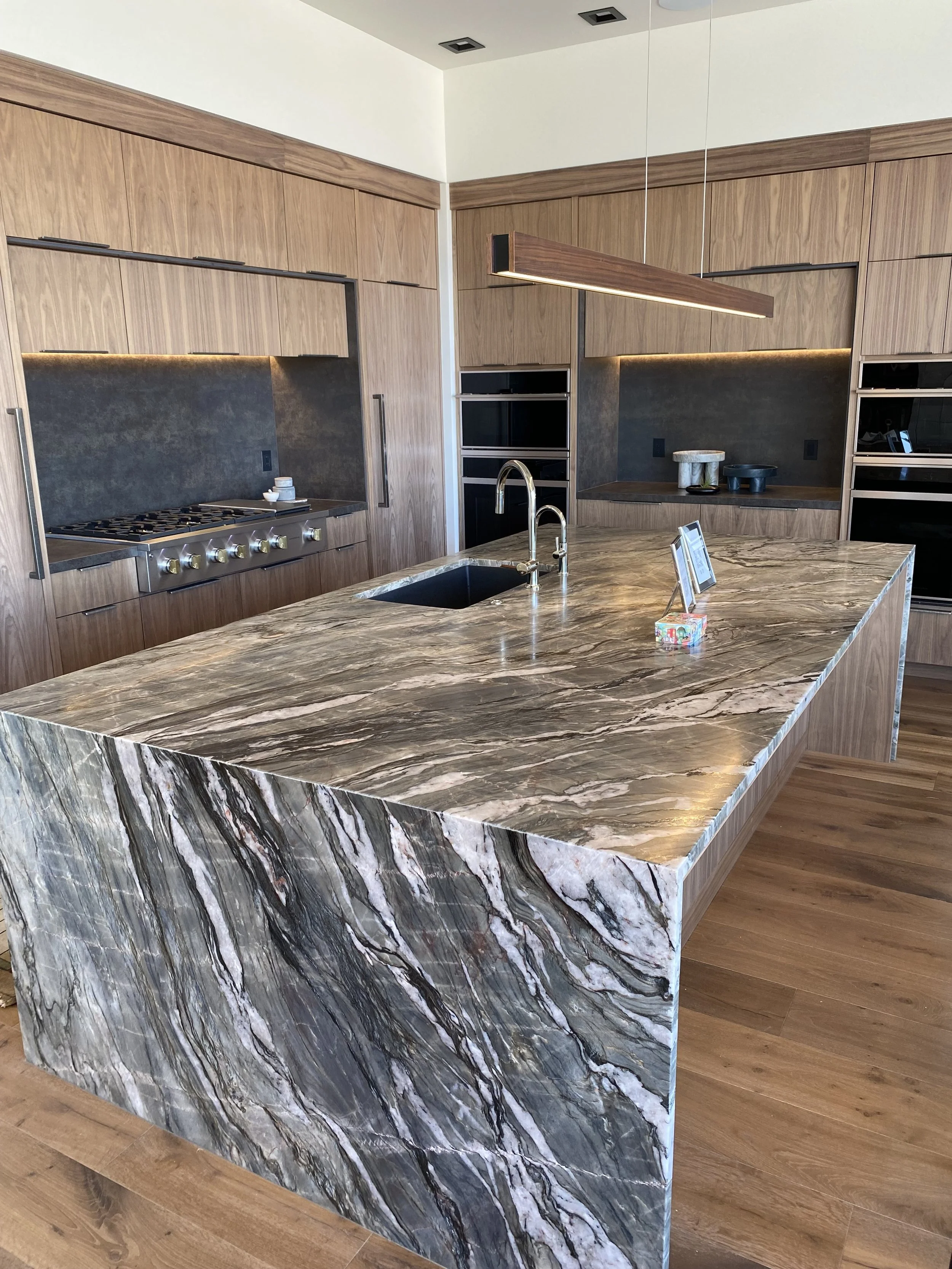 Kitchen with quartzite island, neolith perimetric, and waterfall legs