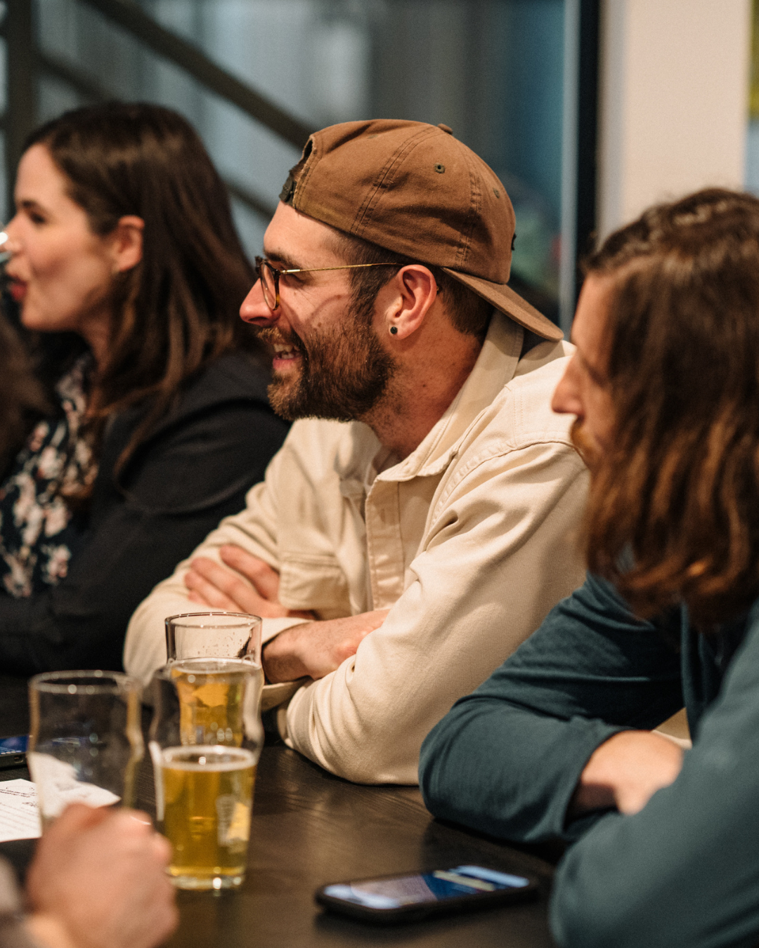 People sitting at a table, smiling, with drinks, in a social setting.