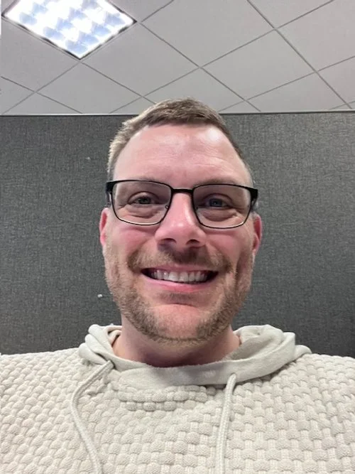 Young man wearing glasses, smiling into the camera