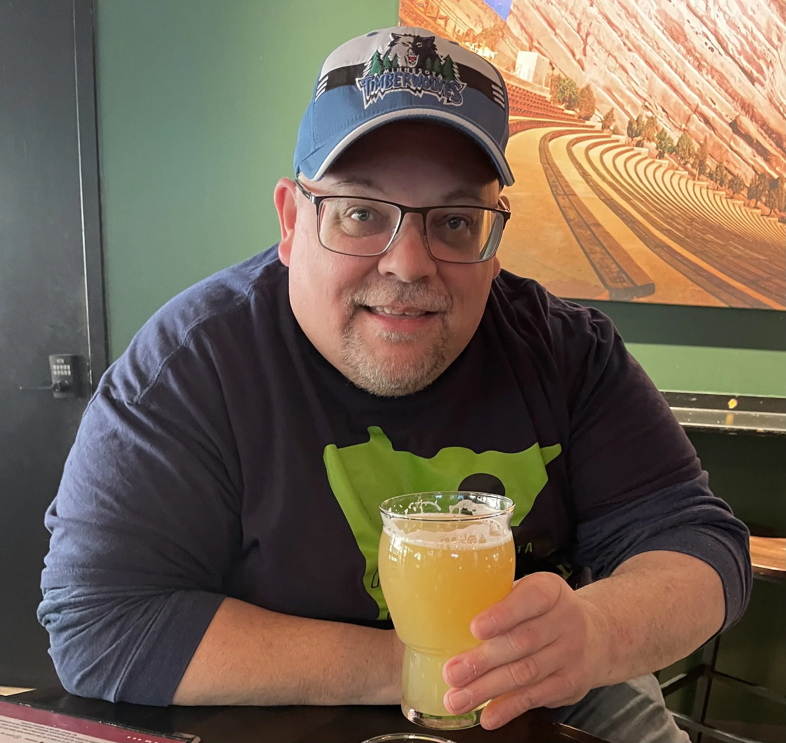 Middle-aged man smiling while holding a full glass of beer