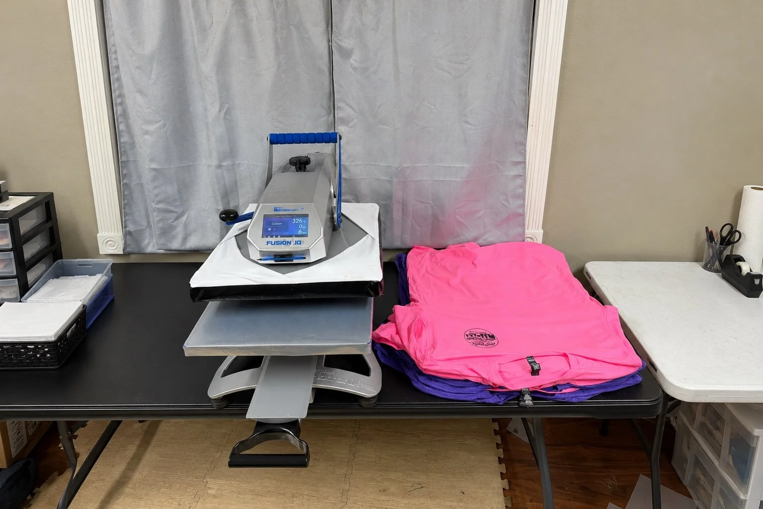 A medical or veterinary examination table with a pink and purple smock, a digital weight scale, and medical supplies in a clinical room.