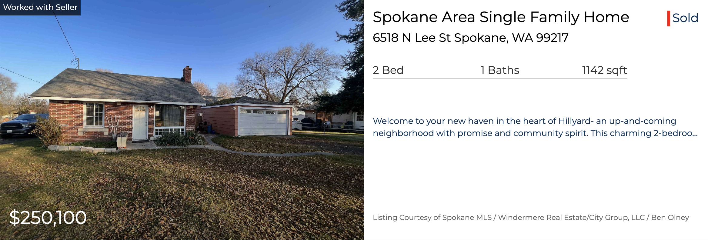 Front view of a brick house with a small front yard, a concrete walkway, and a detached garage, under a clear blue sky with leafless trees in the background.