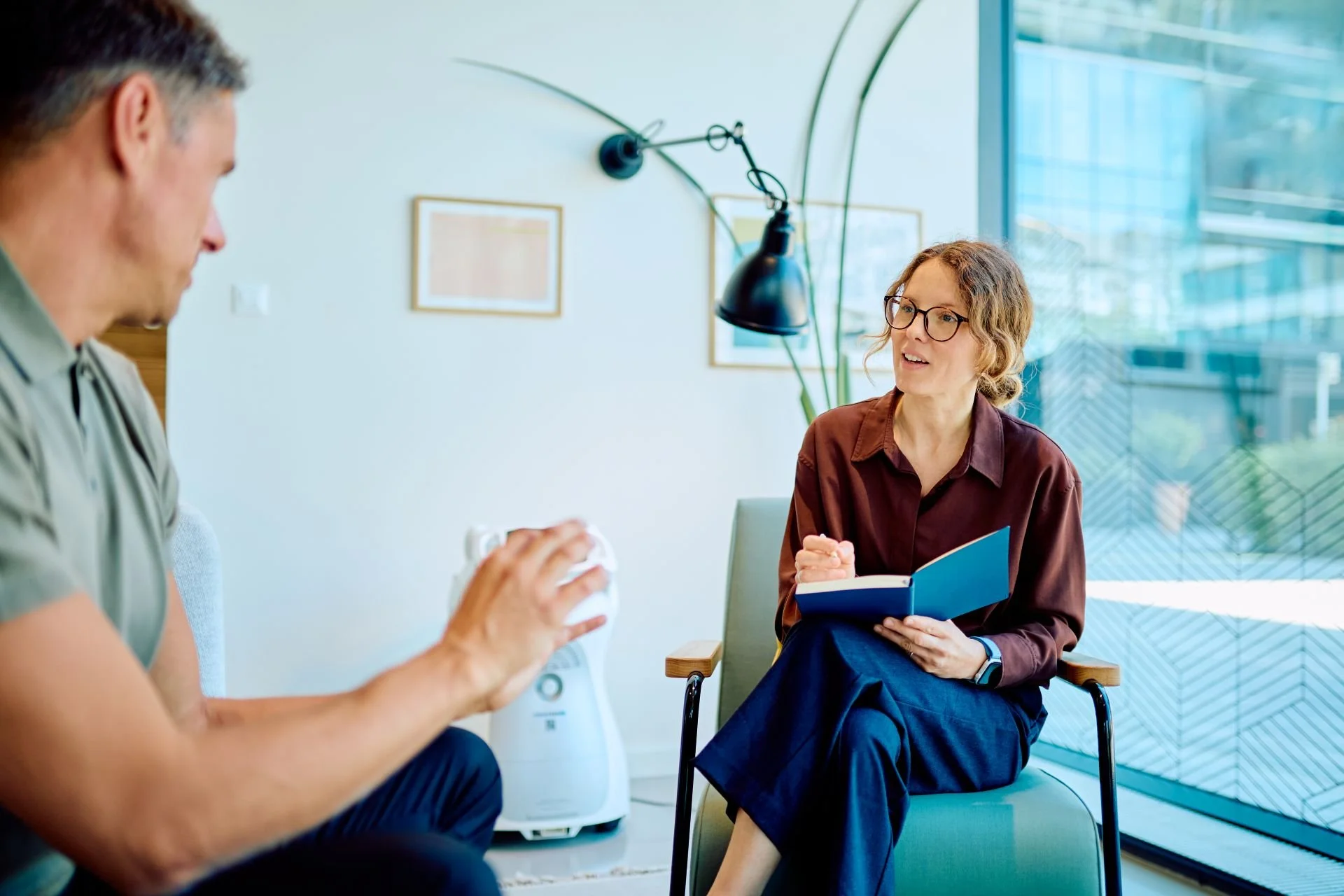 A professional female therapist taking notes during a mental health counseling session for PTSD ketamine therapy.