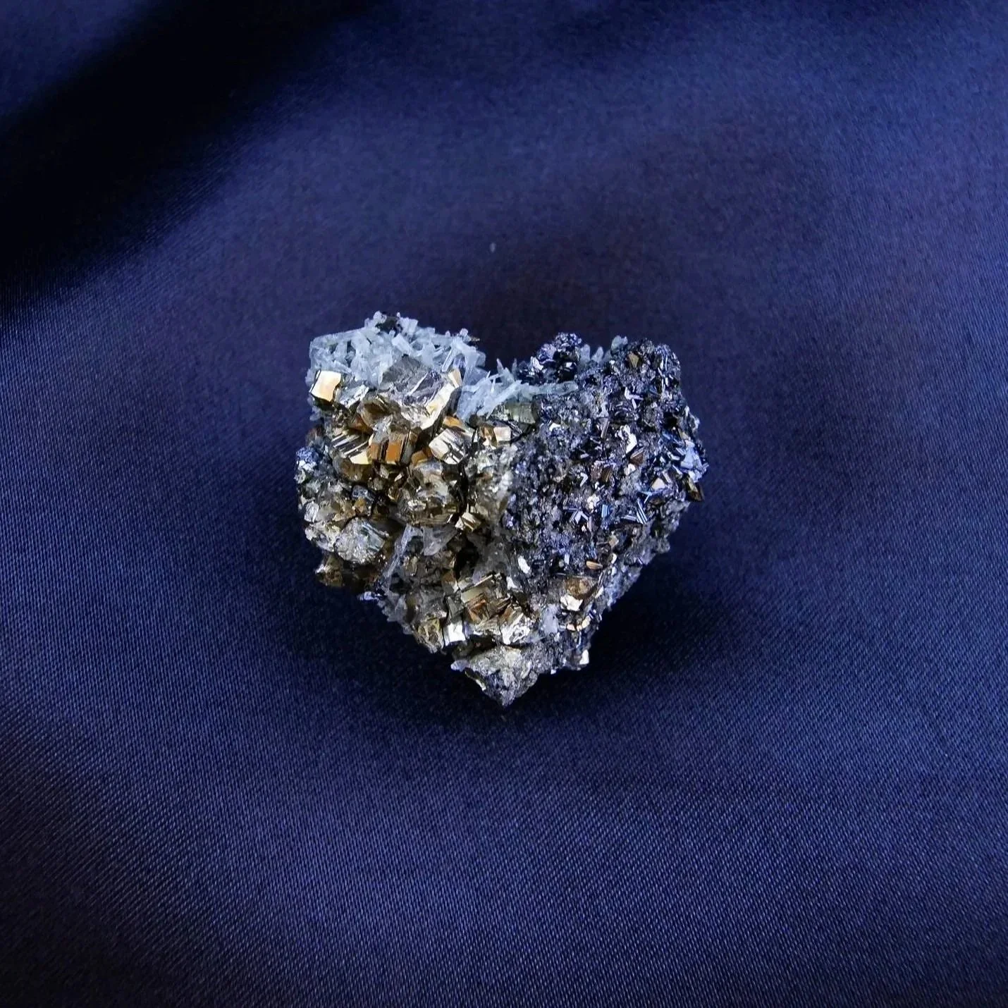 A small cluster of what appears to be a mineral or crystal formation resting on a dark, textured fabric surface.