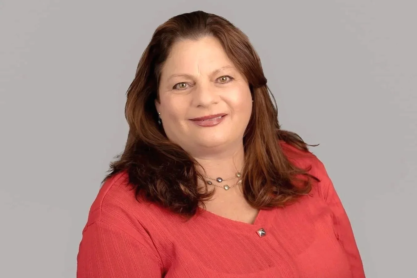 Pam Golden, a professional headshot photo of Pam, Senior Family Law Clerk at Drake Law Family Lawyers, smiling, in formal attire, in front of grey background.