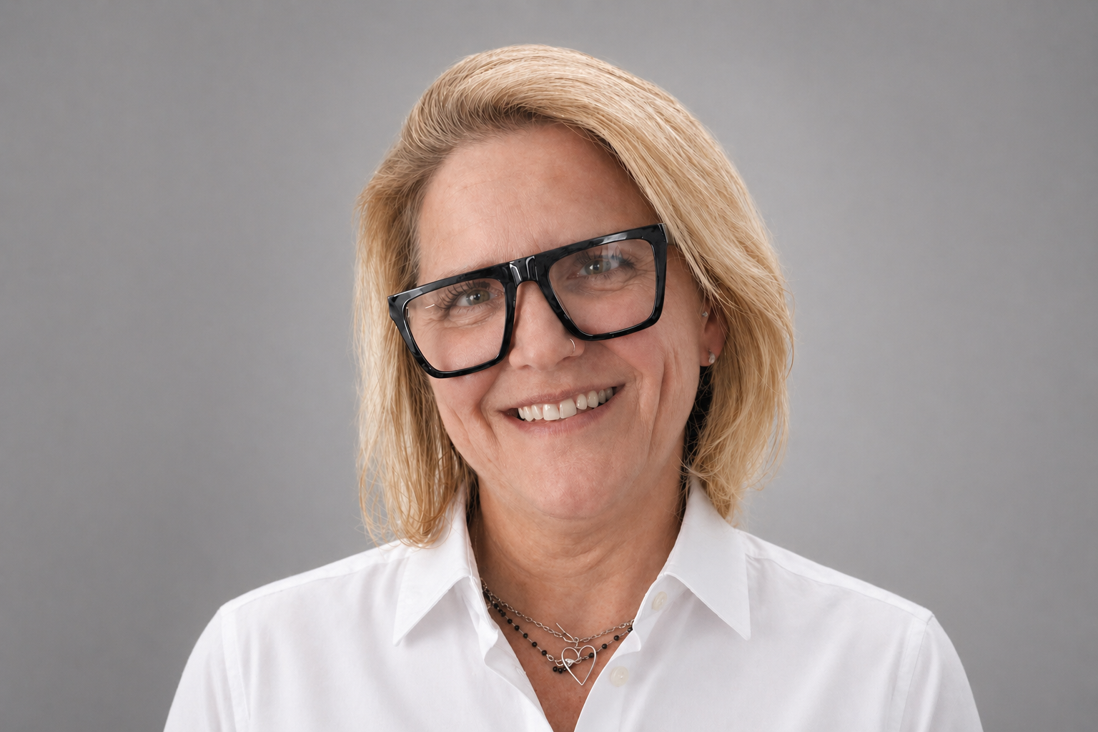 Professional headshot photo of Kira Berry smiling. Black and white with grey background.