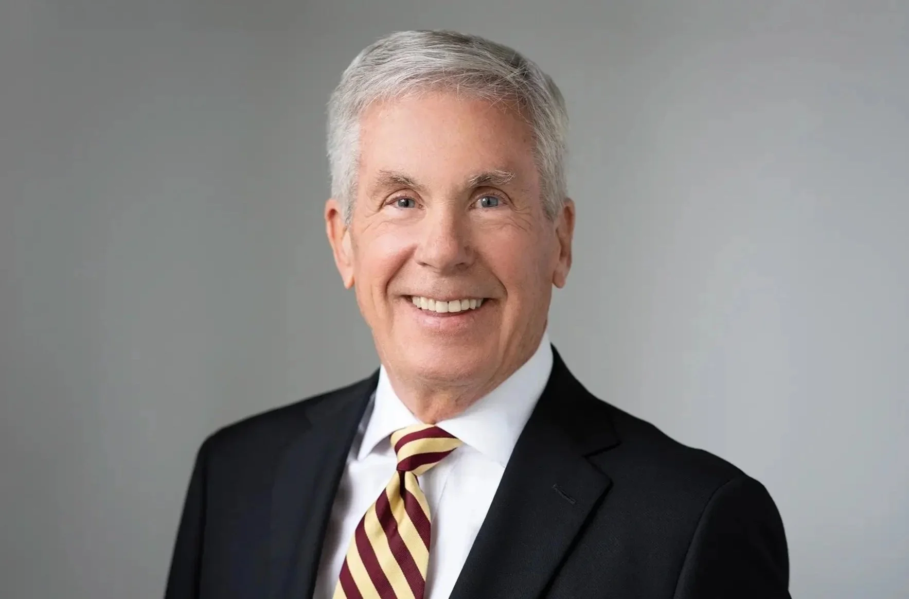 John C. Drake, Senior Counsel - A headshot photo of John dressed in a suit, smiling.