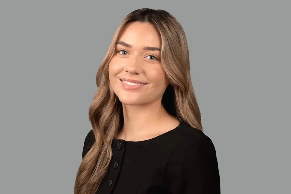 Lauren Jackson, Executive Assistant to CEO, a professional headshot photo of Lauren, smiling, in formal attire, on grey background.