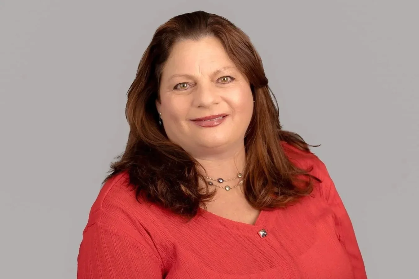 Pam Golden, a professional headshot of Pam Golden, Senior Family Law Clerk at Drake Law Family Lawyers, in formal attire, smiling, on grey background.