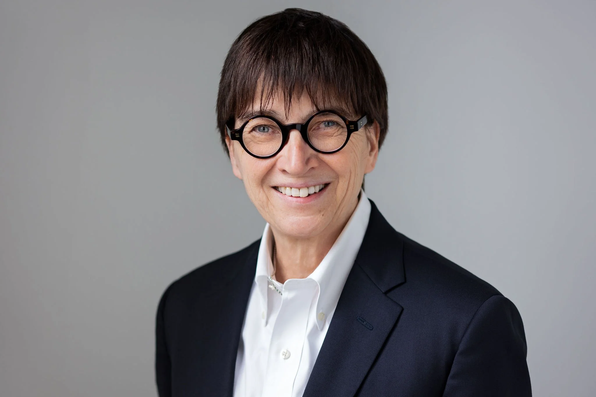 Tinnish Andersen, Senior Counsel, Family Lawyer, a professional headshot of Tinnish in a white shirt, a dark navy blazer, and glasses, smiling.