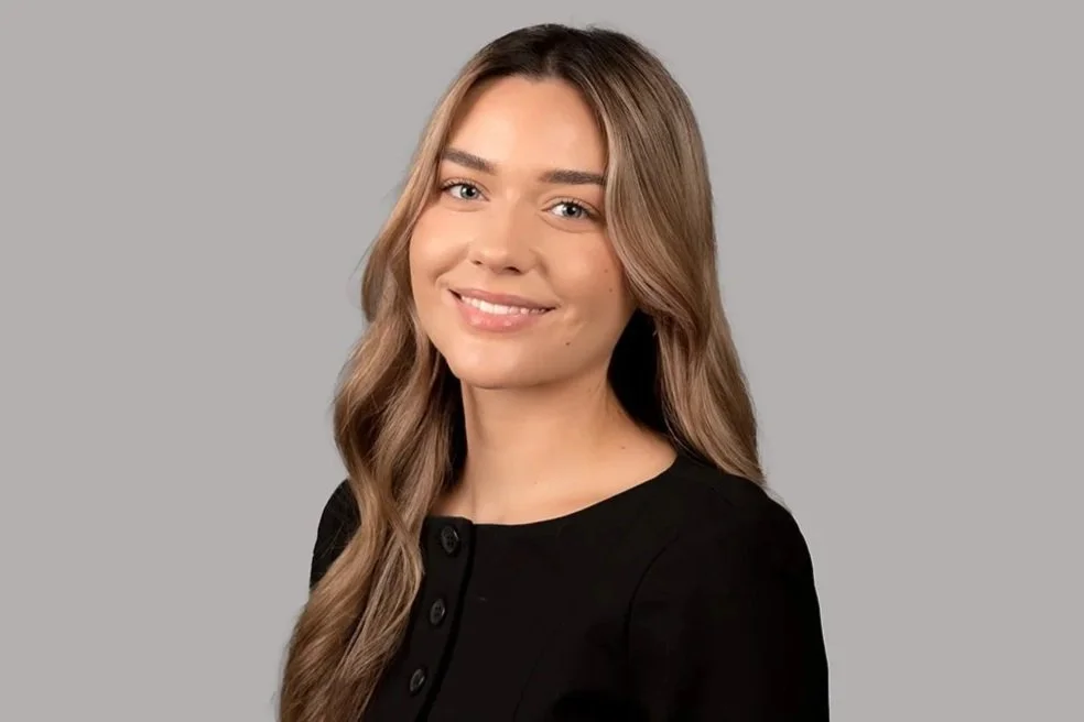 Lauren Jackson, Executive Assistant to CEO, a professional headshot photo of Lauren, smiling, in formal attire, on grey background.