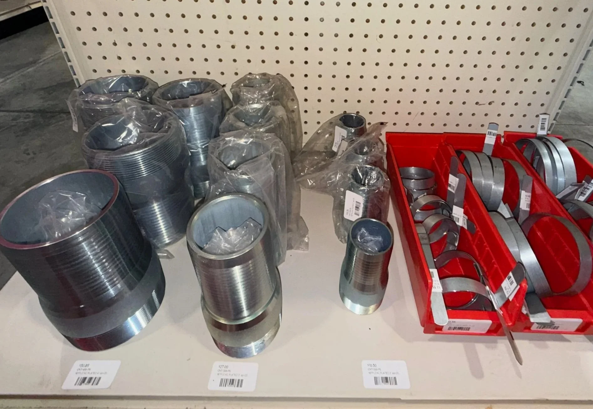 Stacked metal push-in pipe fittings and curved pipe clamps on a display shelf at a hydraulics store., hydraulic products and accessories for sale in Chester, WV, Pittsburgh tri-state area hydraulics shop and supplies
