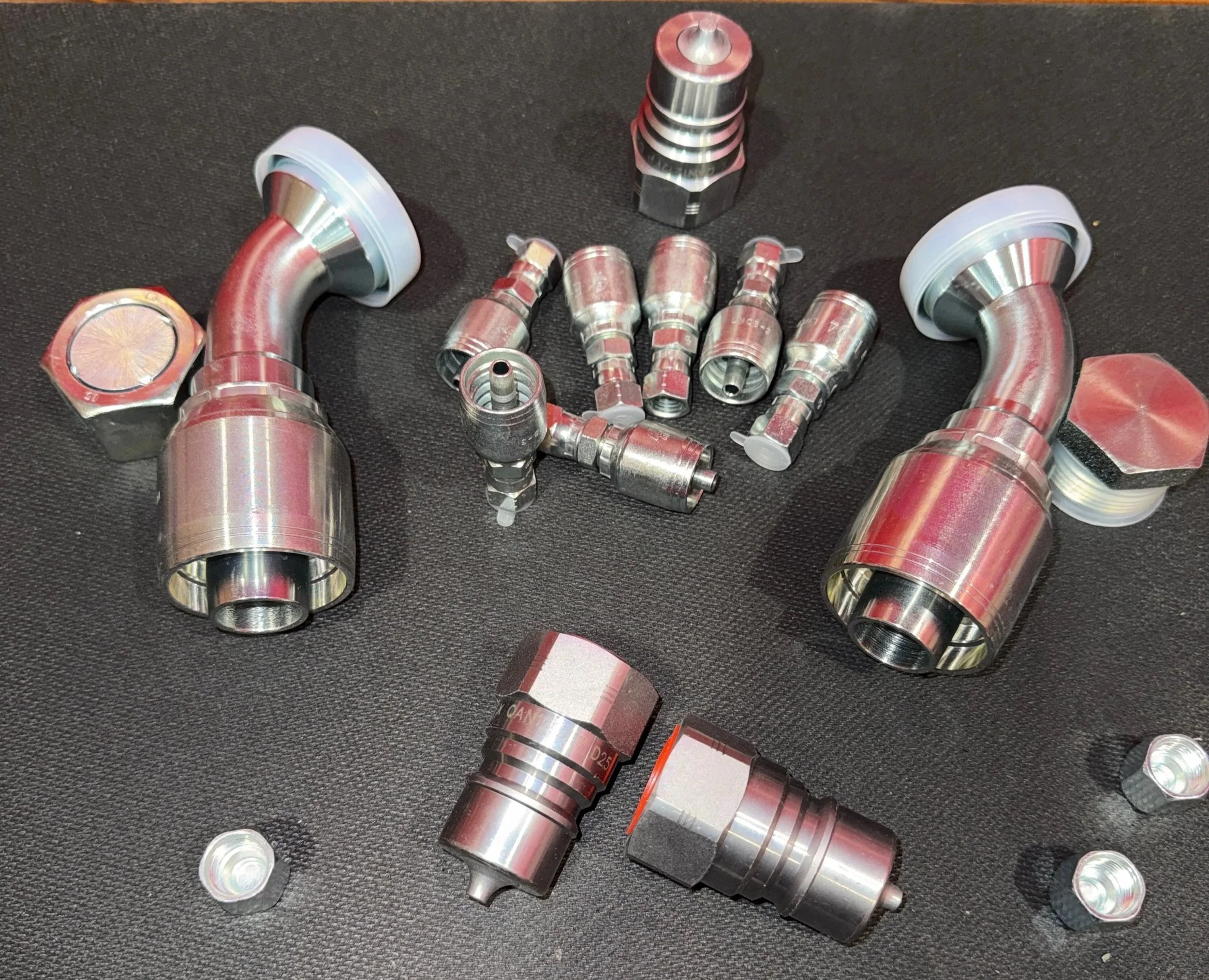 Various metal hydraulic or pneumatic fittings and connectors on a black surface, Chester West virginia hydraulic shop products and accessories