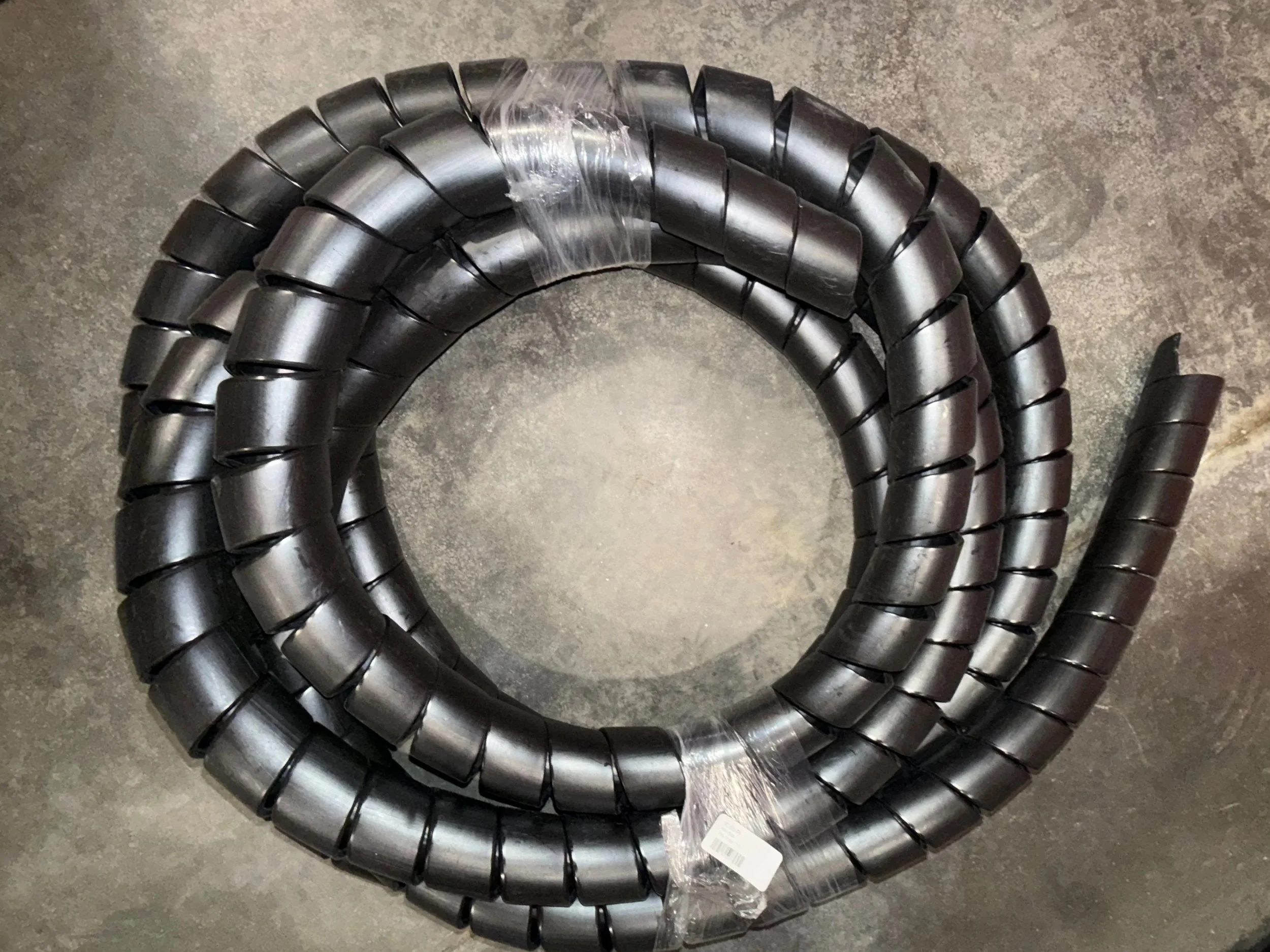 Hydraulic product for sale, A coil of black rubber hose or tubing, loosely coiled on a gray concrete floor, Chester West virginia hydraulic shop product