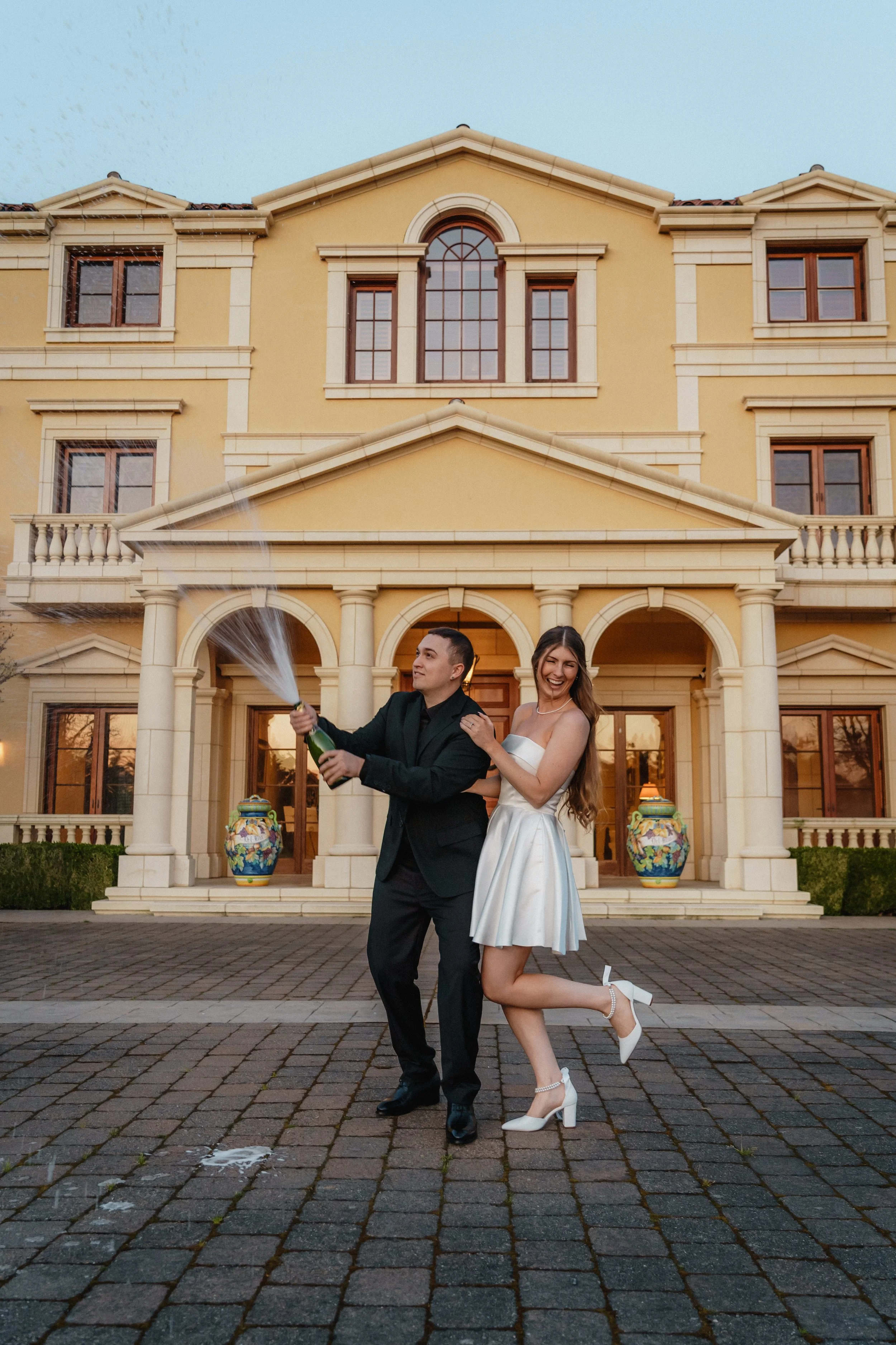 Couple smiling with foreheads touching, outdoors with forest background.