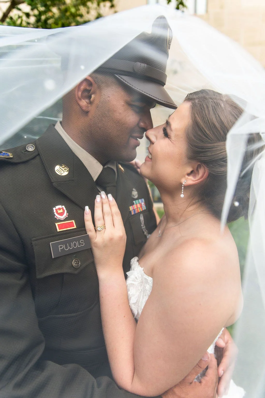 Bride and groom sharing a first kiss under a bridal veil, at their outdoor wedding in Kansas City, Missouri