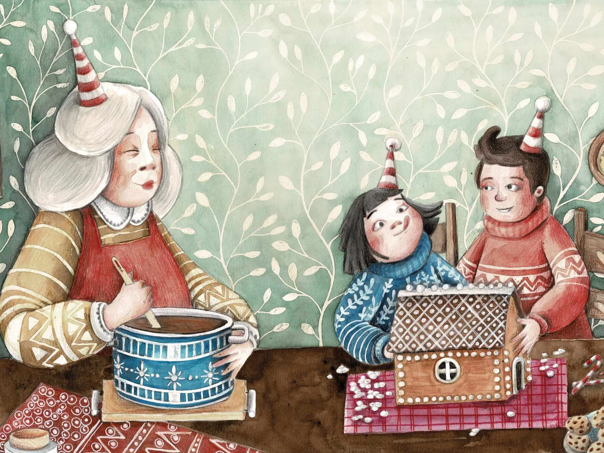 Una donna con capelli grigi e un cappello con un cono natalizio, che mescola qualcosa in una grande ciotola azzurra, mentre due bambini con cappelli natalizi e felpe colorate sono seduti a una tavola decorata, apparentemente parlando e sorridendo.