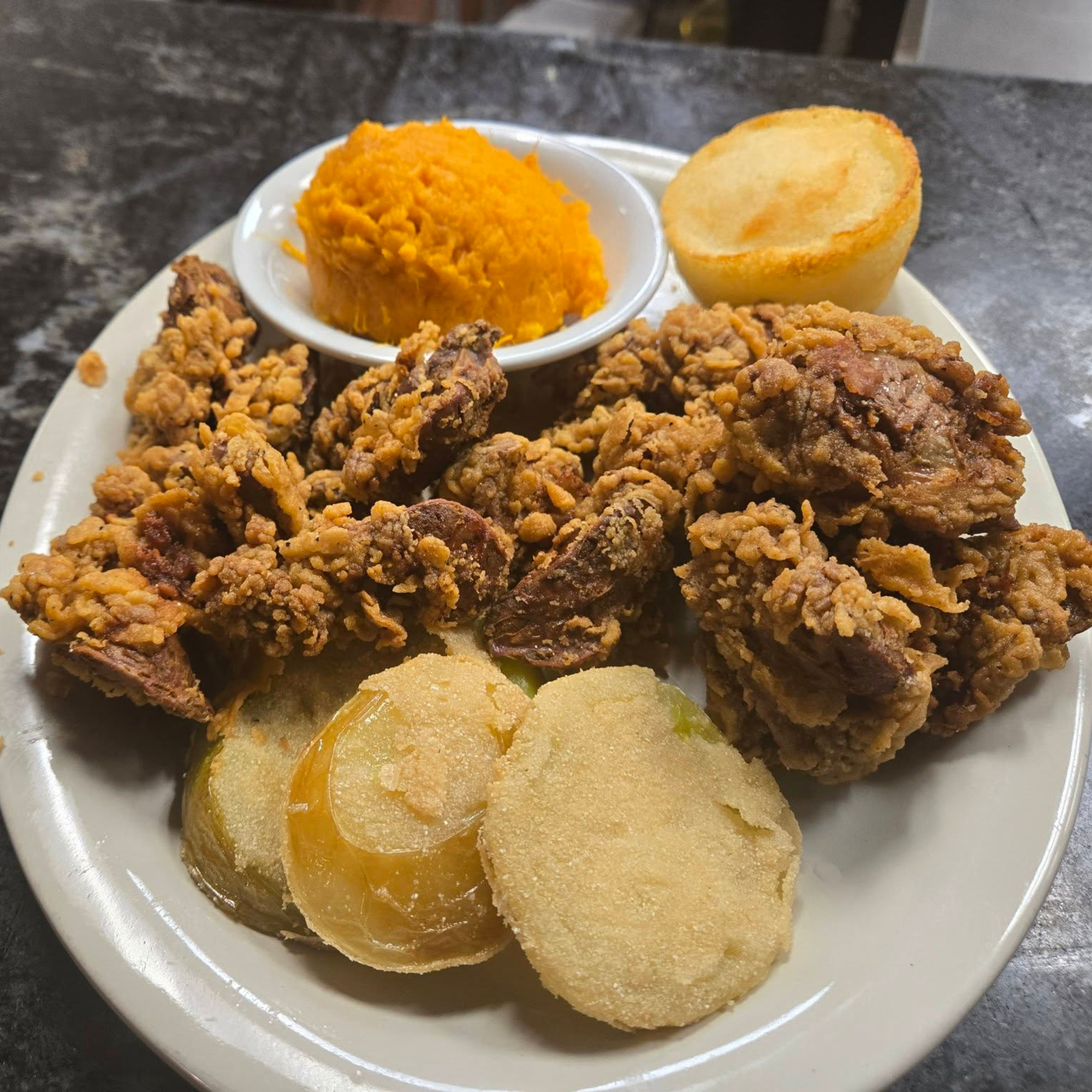 Plate with fried chicken, mashed sweet potatoes in a small bowl, and slices of cooked yellow squash.