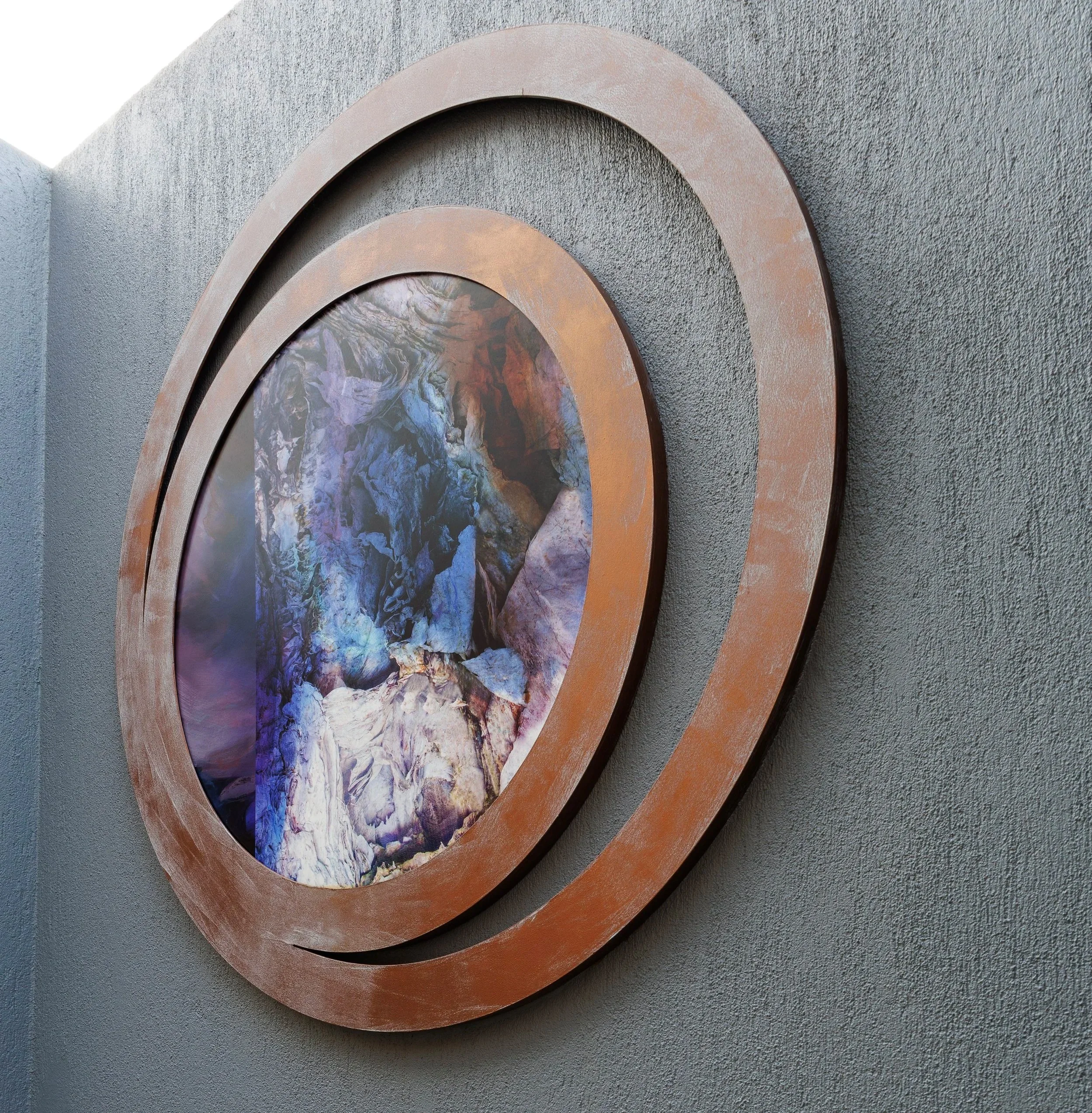 Close-up of abstract artwork featuring concentric oval shapes with textured surfaces, set against a speckled gray background.