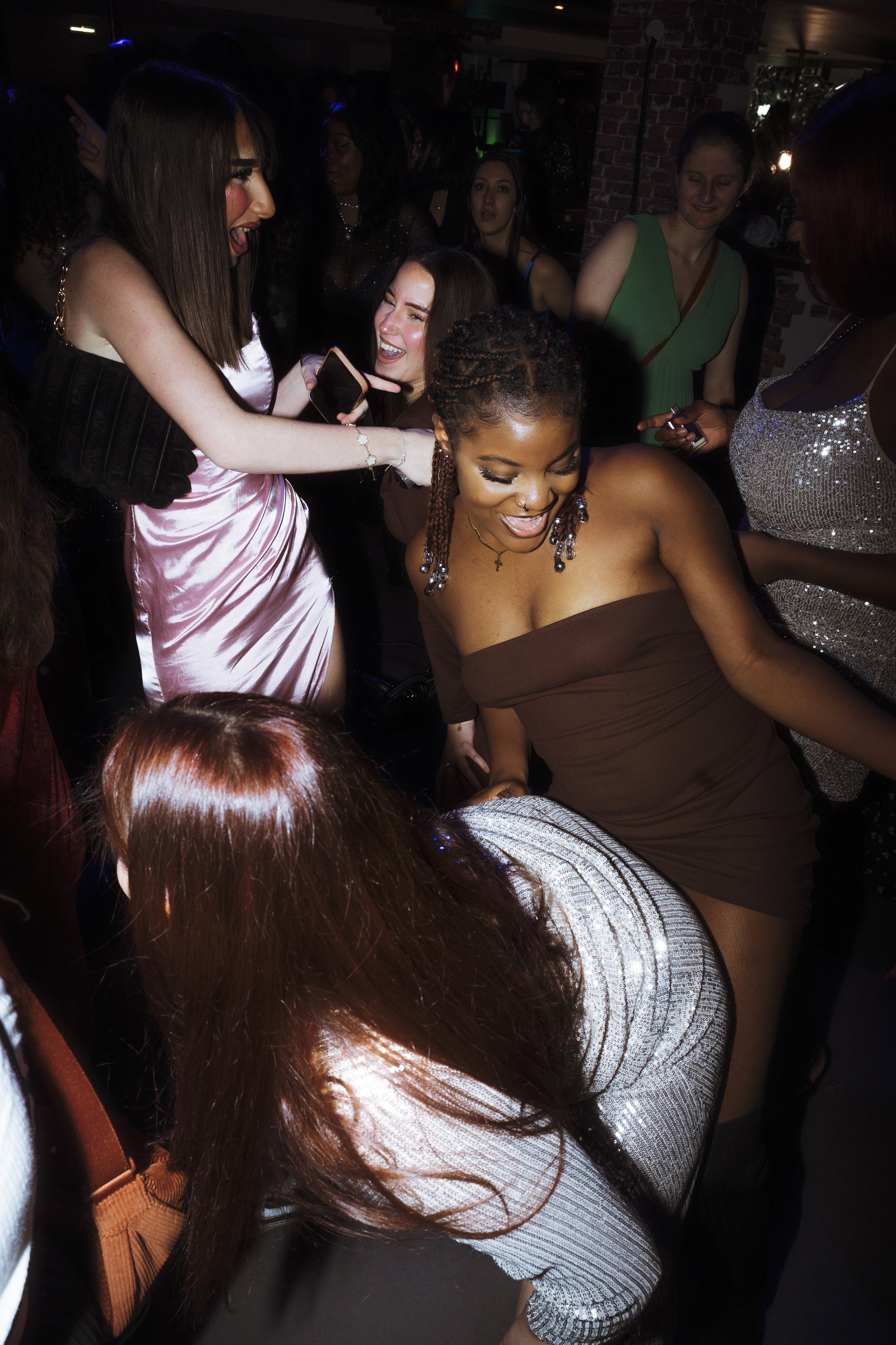 Groupe de femmes dansant en soirée, portant des robes élégantes et souriant.