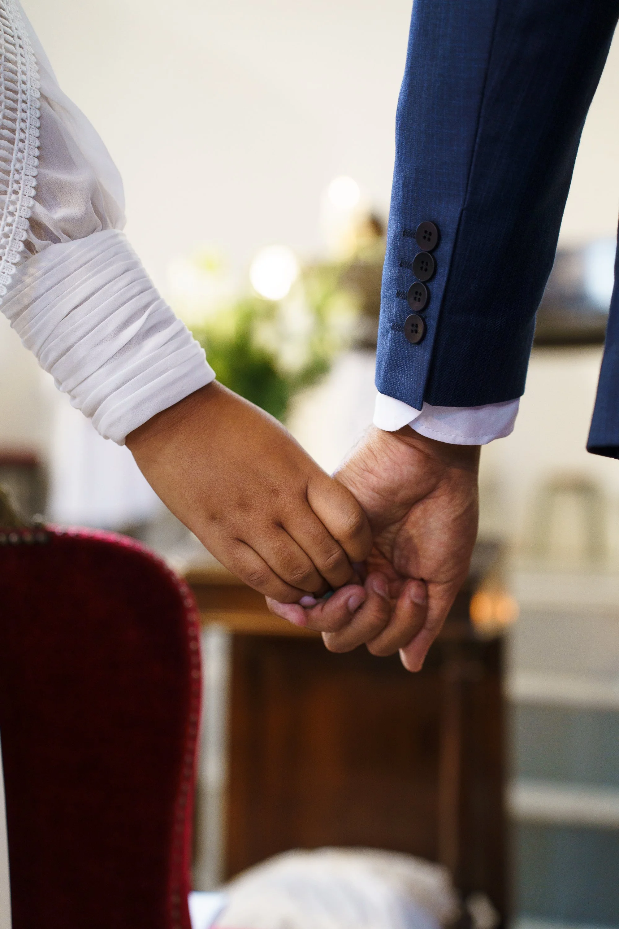 Une personne en costume homme et une personne en blouse blanche se tiennent la main lors d'une cérémonie ou d'un mariage.