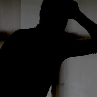 Eine silhouettenhafte Person lehnt an einer Wand, mit einem arm hinter dem Kopf.