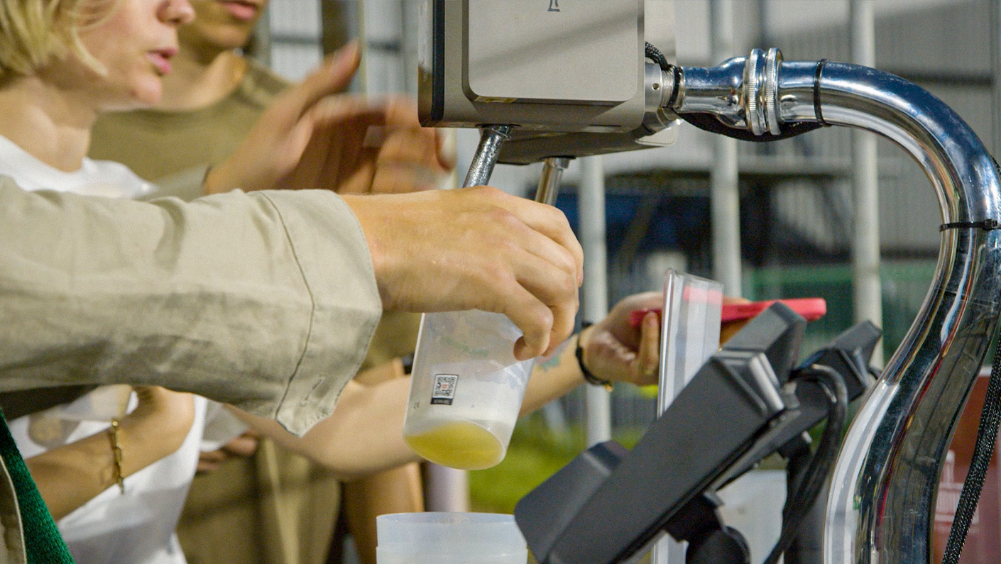 People placing orders at a drive-thru window, with a person holding a drink and a touchscreen terminal.
