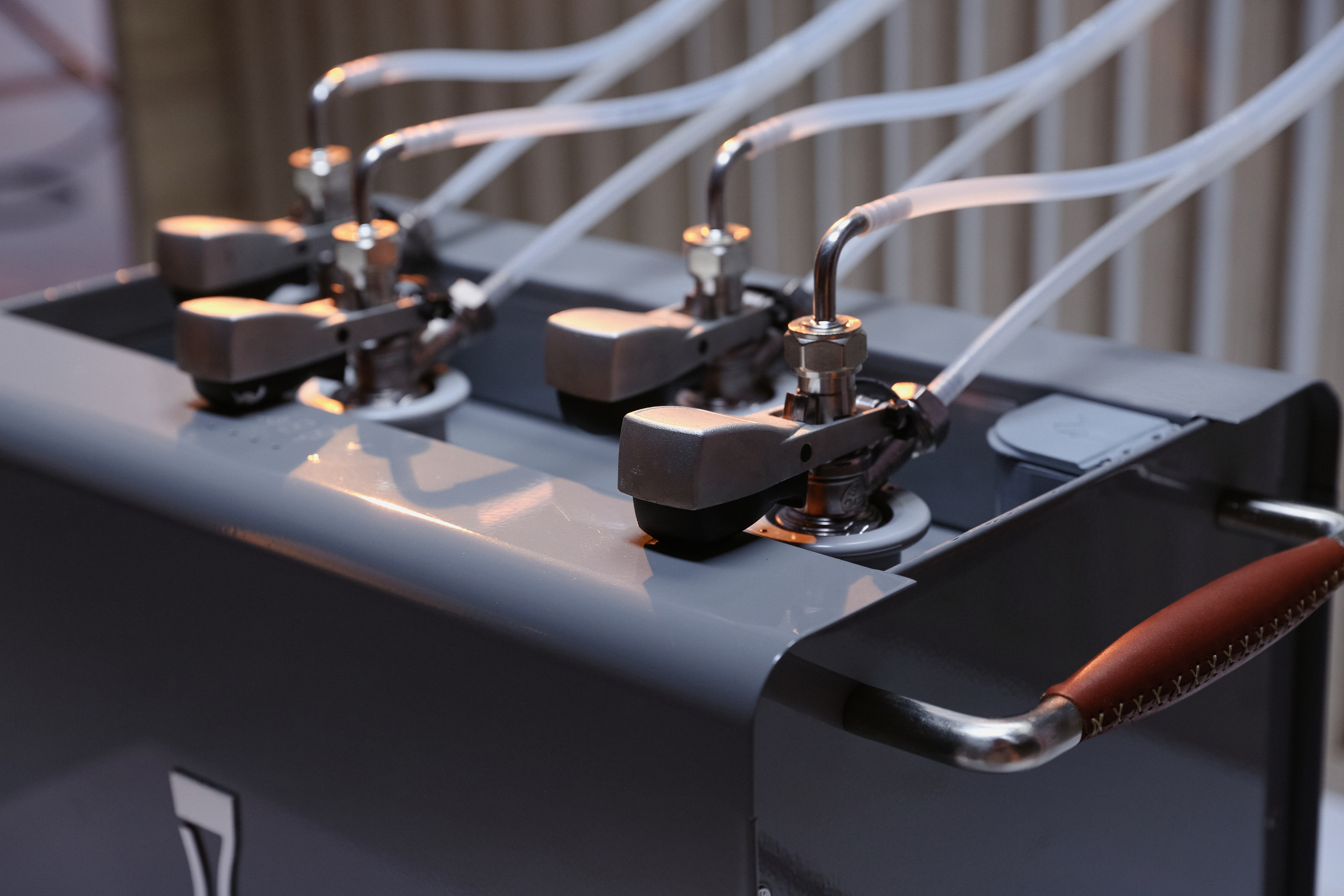 Close-up of an industrial or commercial shoe repair machine with multiple nozzles and tubes connected to it.