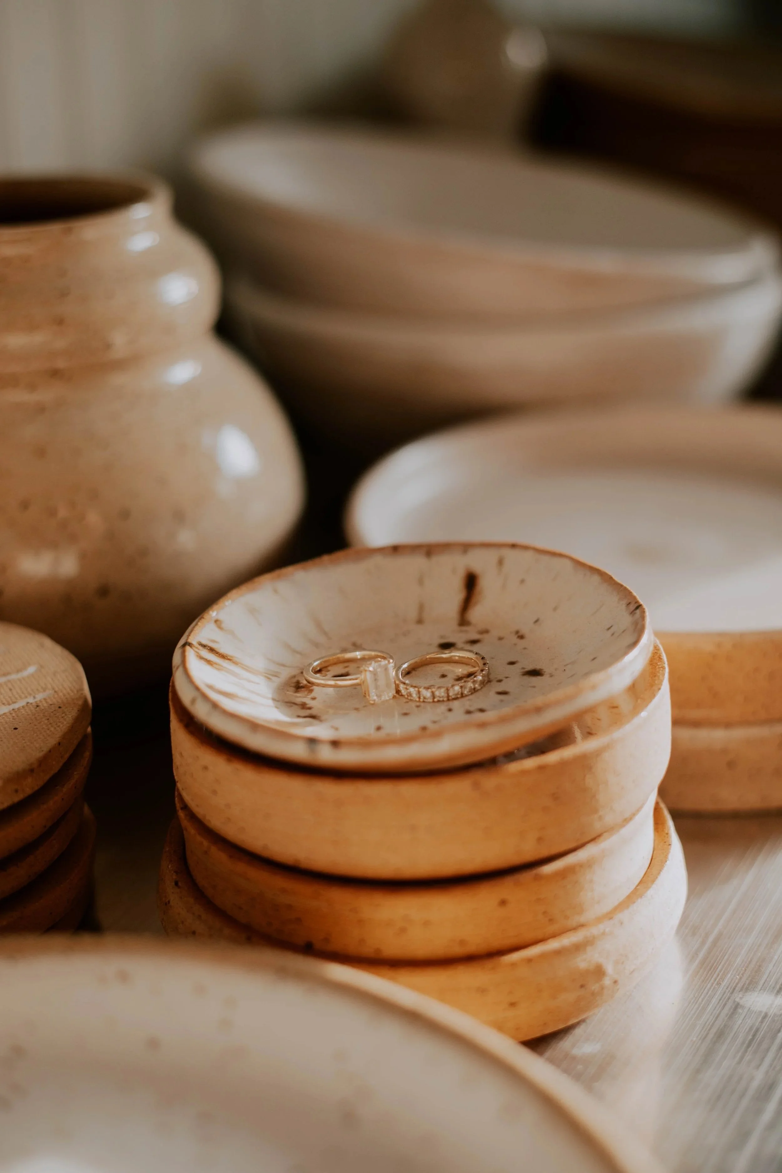 Close-up of stacked wooden bowls and plates, with silver rings resting inside one of the bowls.
