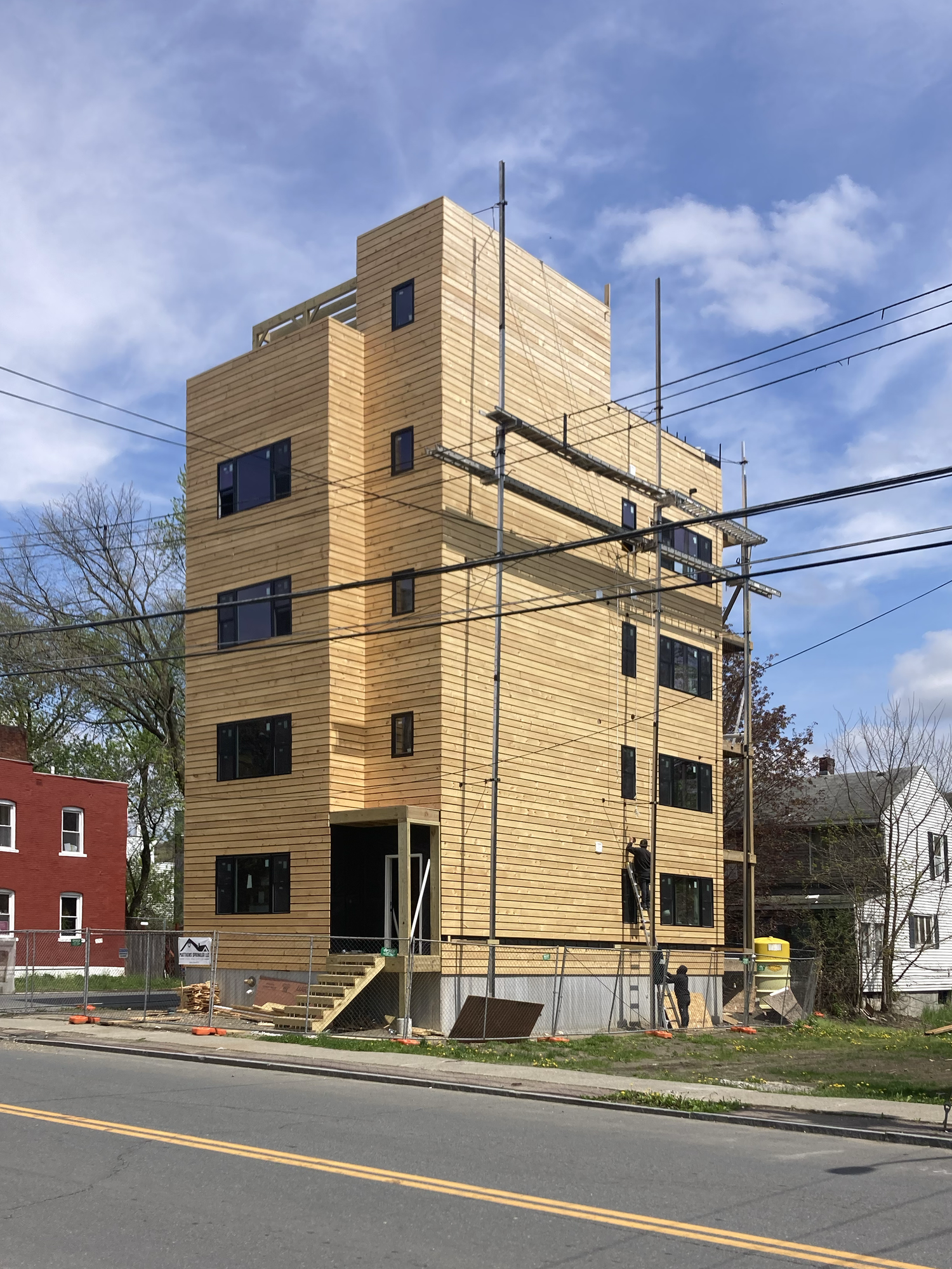 Swift Street Residences in Troy, NY — four-unit affordable housing prototype under construction with open-joint wood cladding and large window openings.