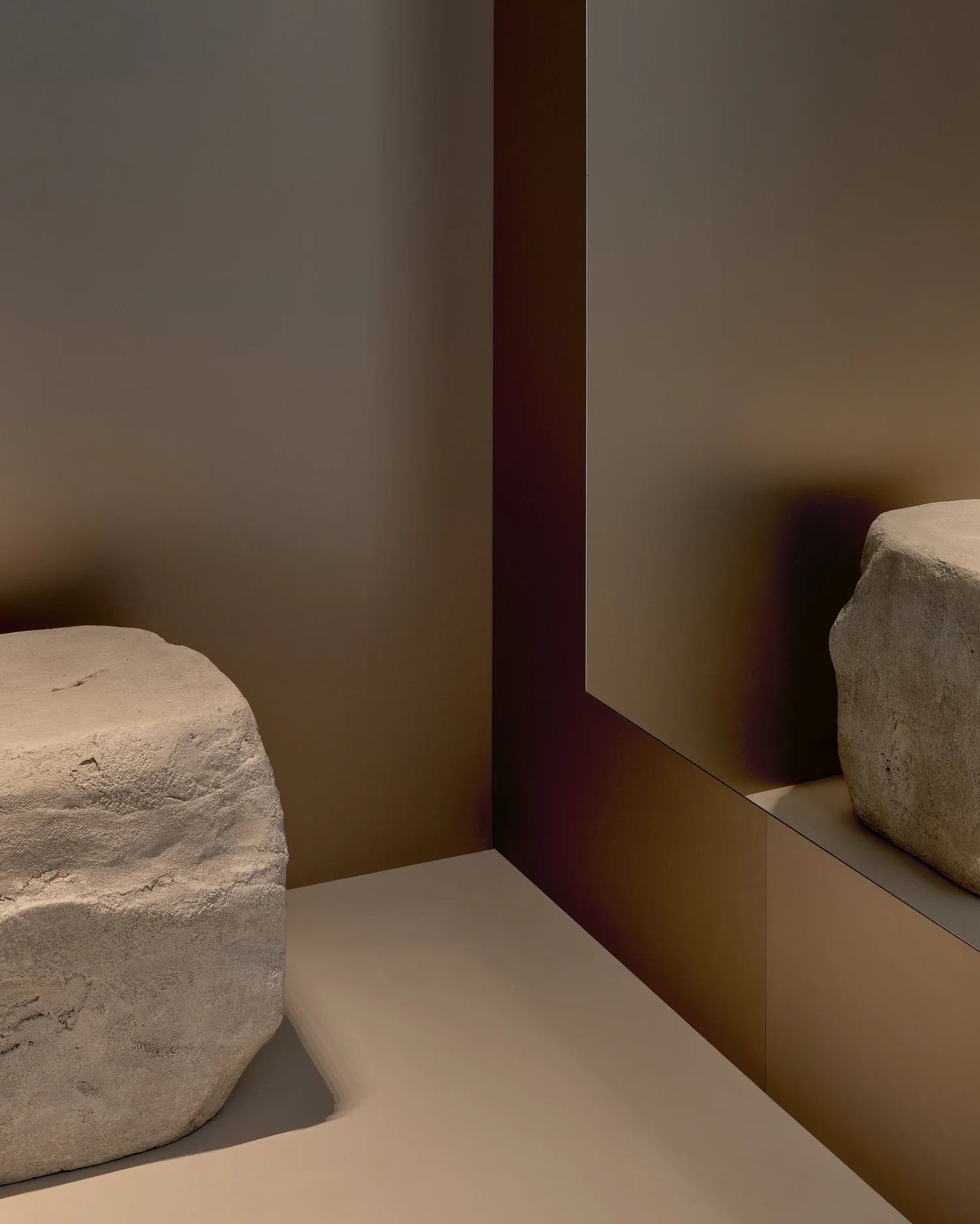 Interior material detail at Madhappy New York Flagship, featuring a natural stone element set against reflective bronze-toned wall panels.
