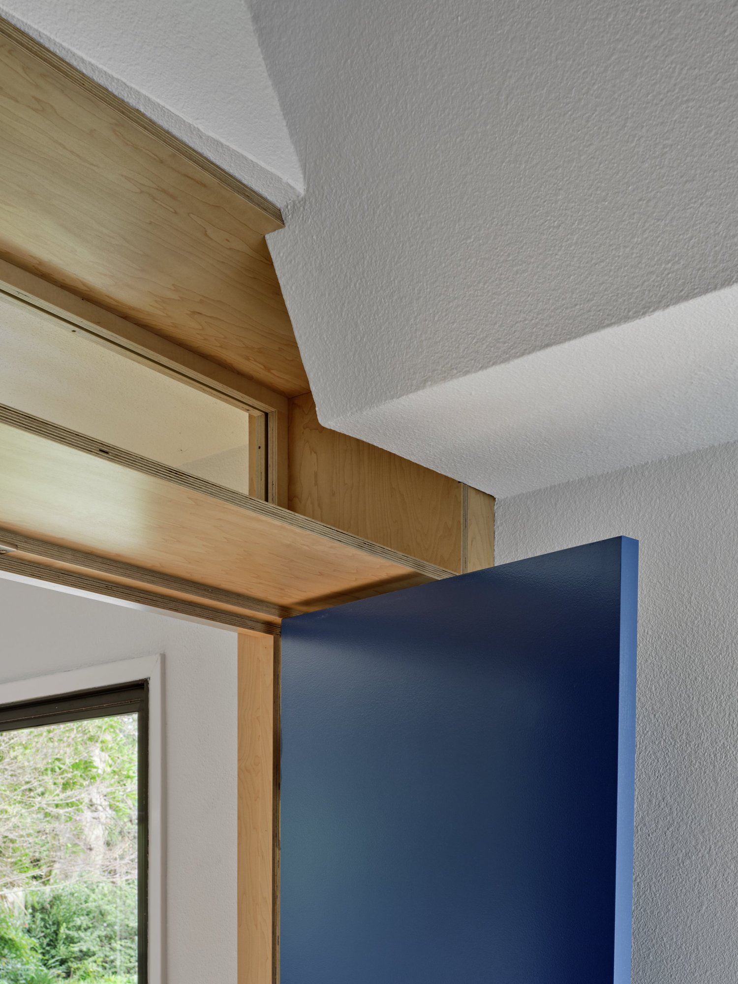 Close-up of Three Cork Walls interior showing a blue door with a wood-framed transom window above, set against a cork wall surface.