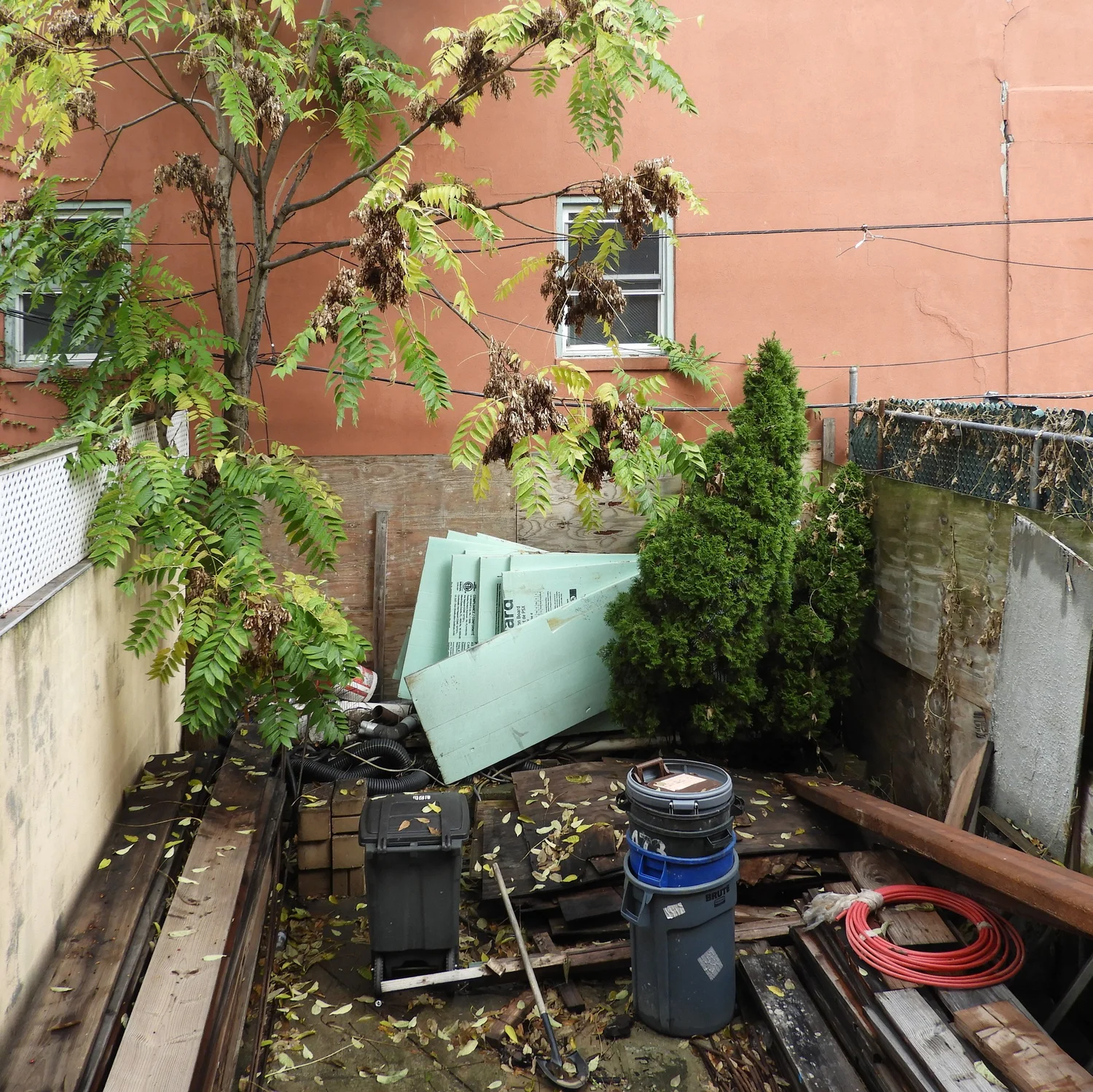 Construction debris and insulation materials in the rear yard of Narrow Townhouse during renovation.