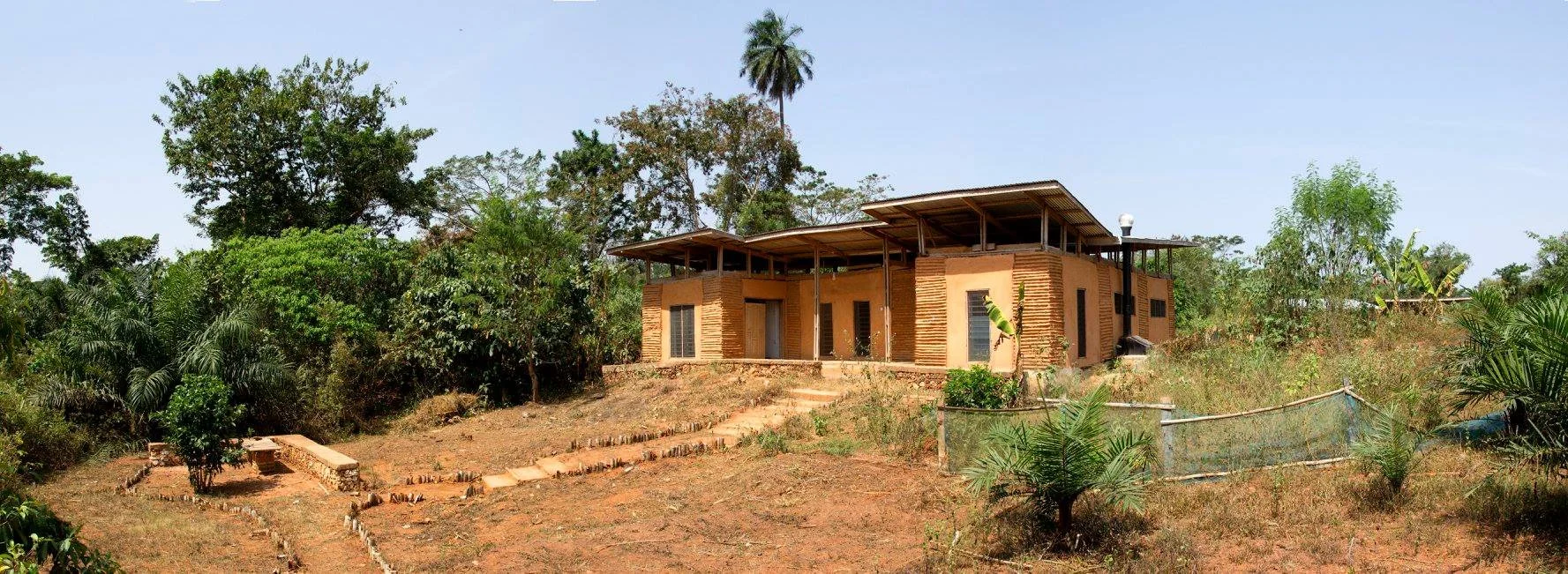 Single-story home with thick earthen walls and a pitched roof set into a hillside.