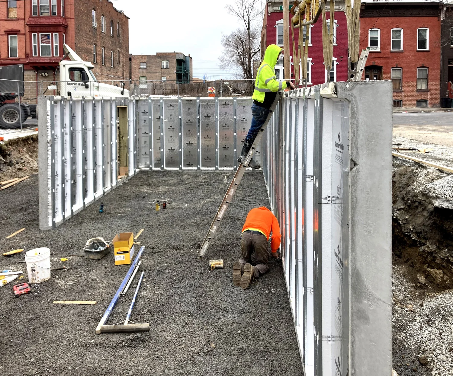 Foundation construction at Swift Street Residences using prefabricated modular concrete wall panels, with workers on site in Troy, New York.