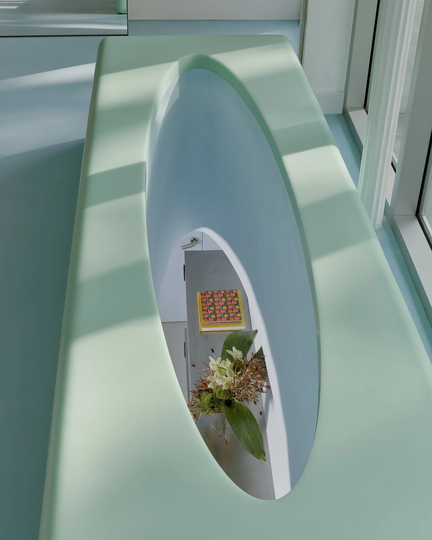 Detail of sculptural mint-green bench at Madhappy New York Flagship, featuring an inset floral display and accessories.