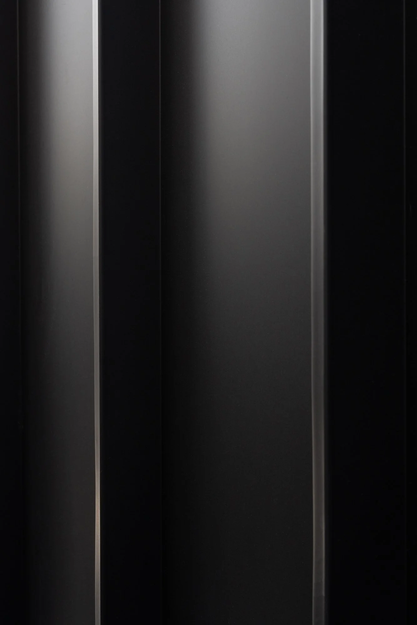Close-up detail of Narrow Townhouse exterior metal siding with matte black vertical panels.