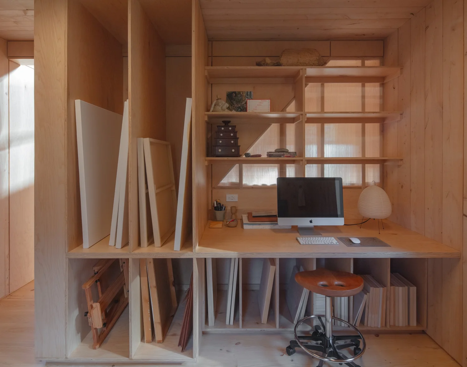 Barnard Barn, Compact office nook built into wooden shelving with vertical and horizontal cubbies, a desk surface, and a computer setup.