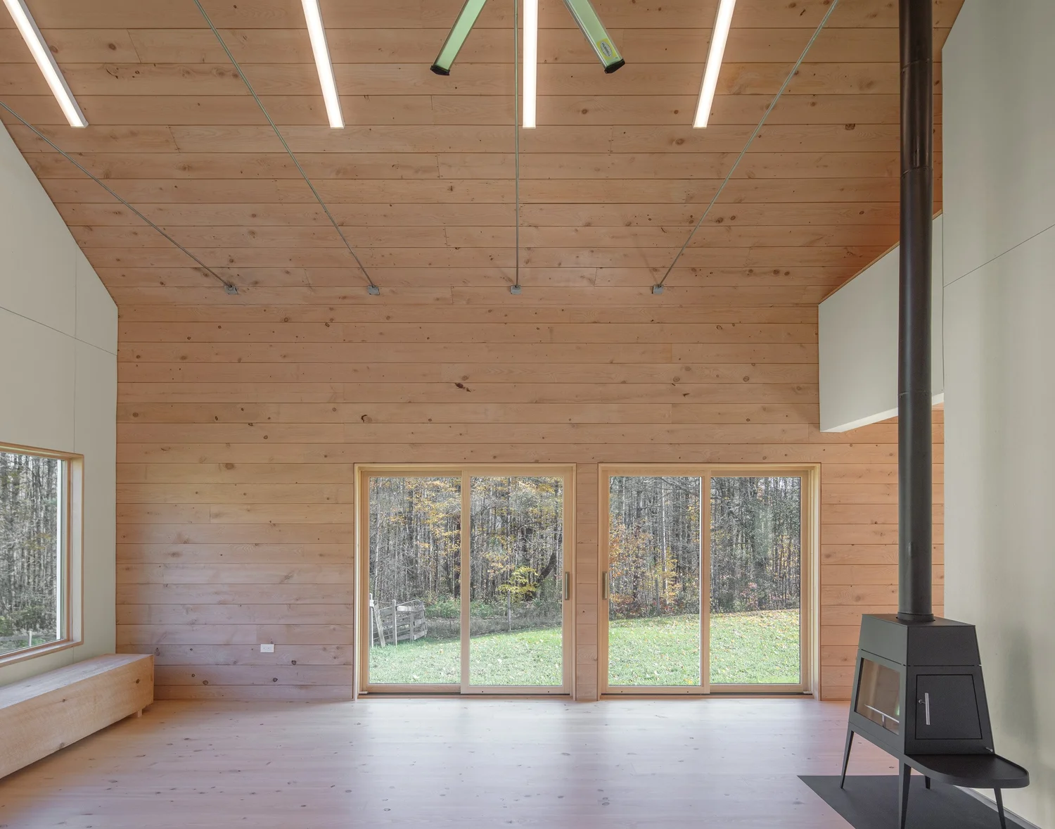 Interior view of Barnard Barn’s loft, with sloped wood ceilings, exposed rafters, linear strip lighting, and a white sofa against the railing. The loft overlooks the double-height barn space below.