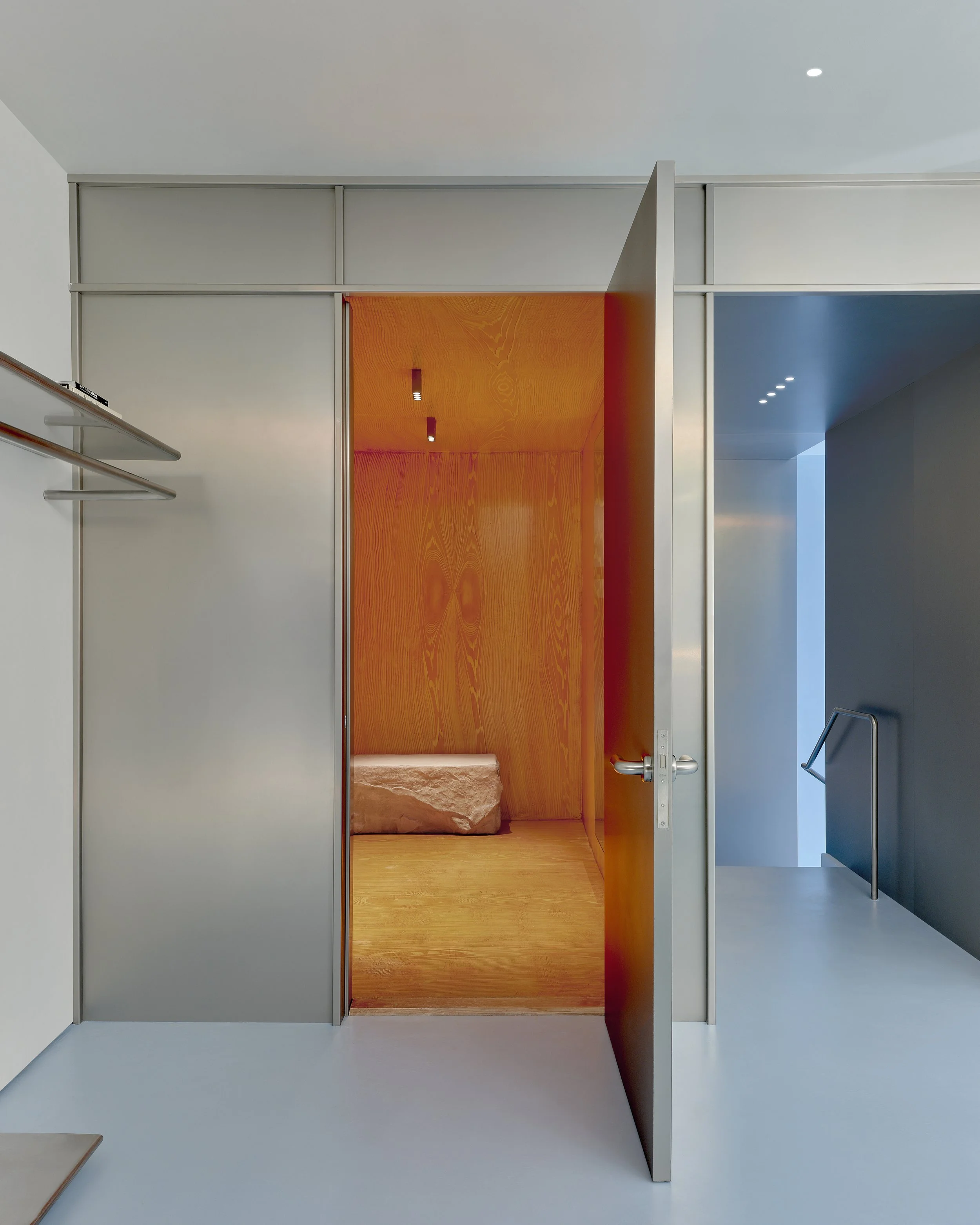 Modern walk-in closet with open shelving and a striking orange accent wall.