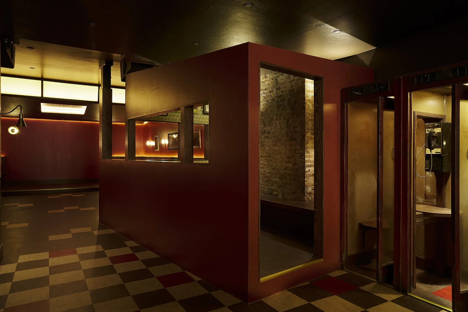Gazebo structure inside Mr. Nancy’s bar with red-painted partitions, interior brick wall seating, and vintage phone booths.