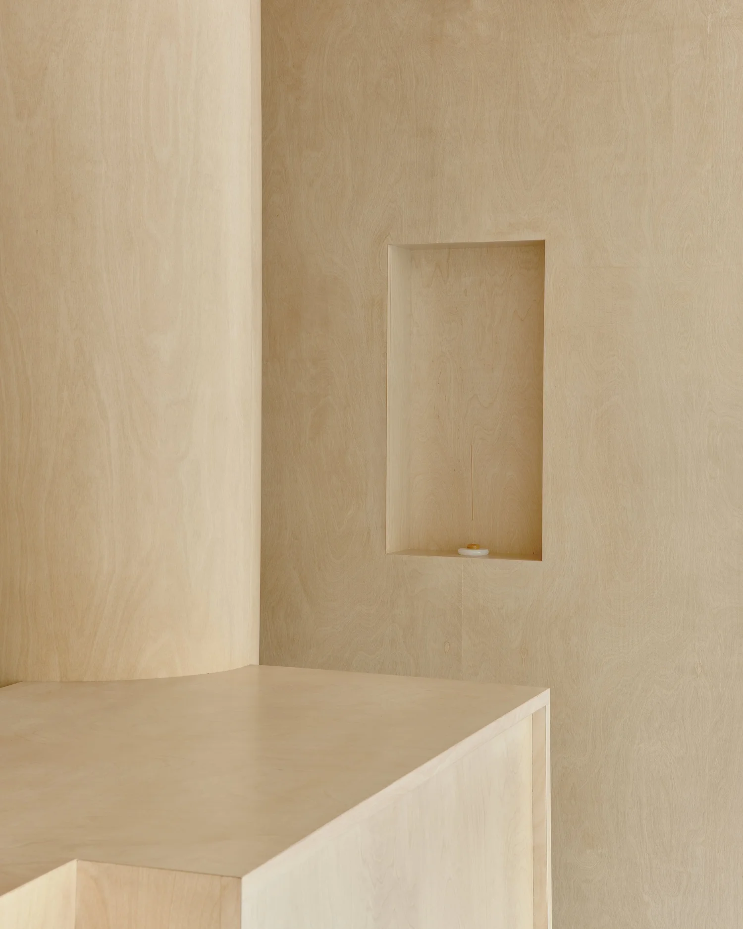 Interior detail of Madhappy New York Flagship with light wood wall, cylindrical column, and recessed display niche.