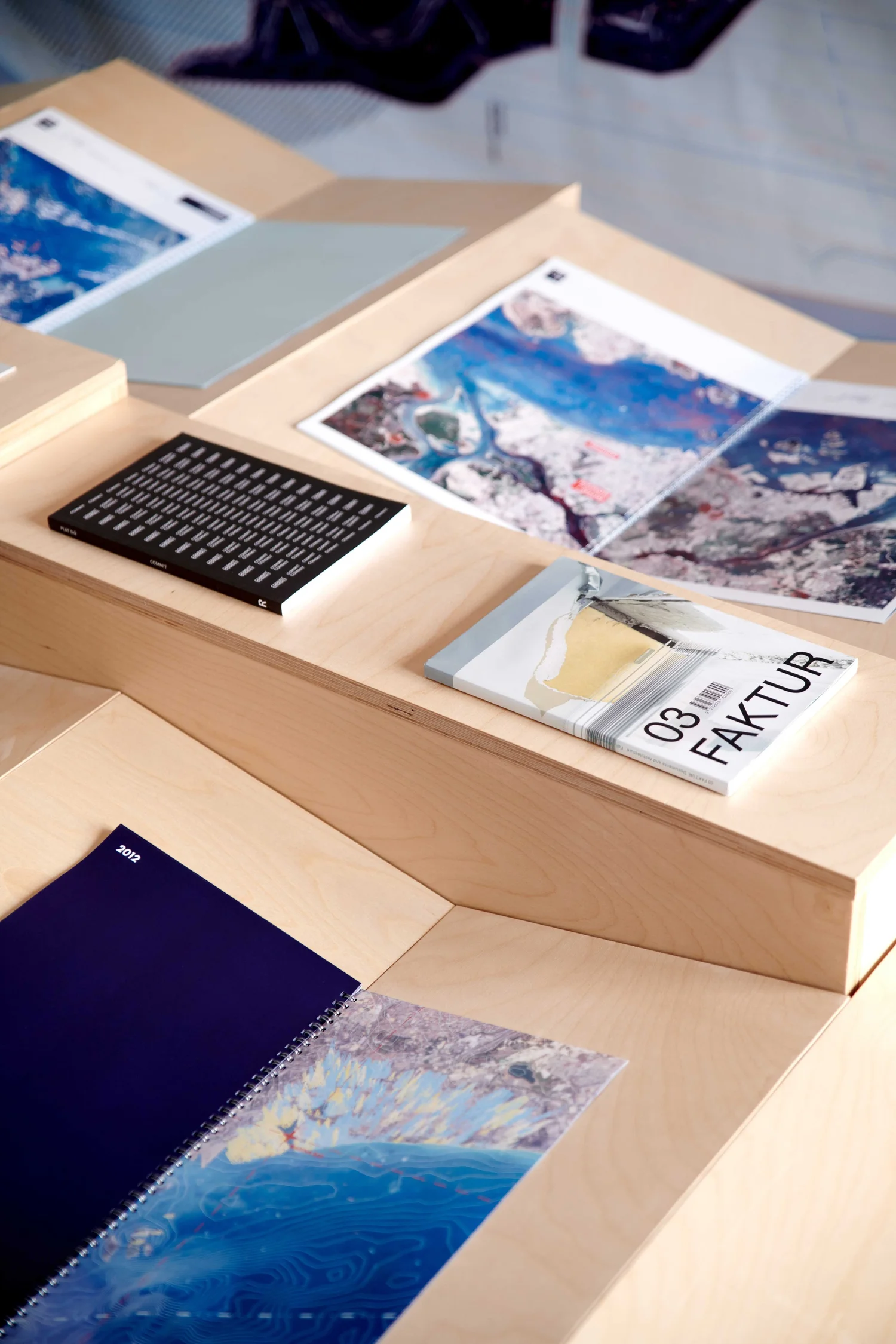 Detail view of Territories of Territory Extraction showing open books with satellite imagery and text on a stepped wood display.