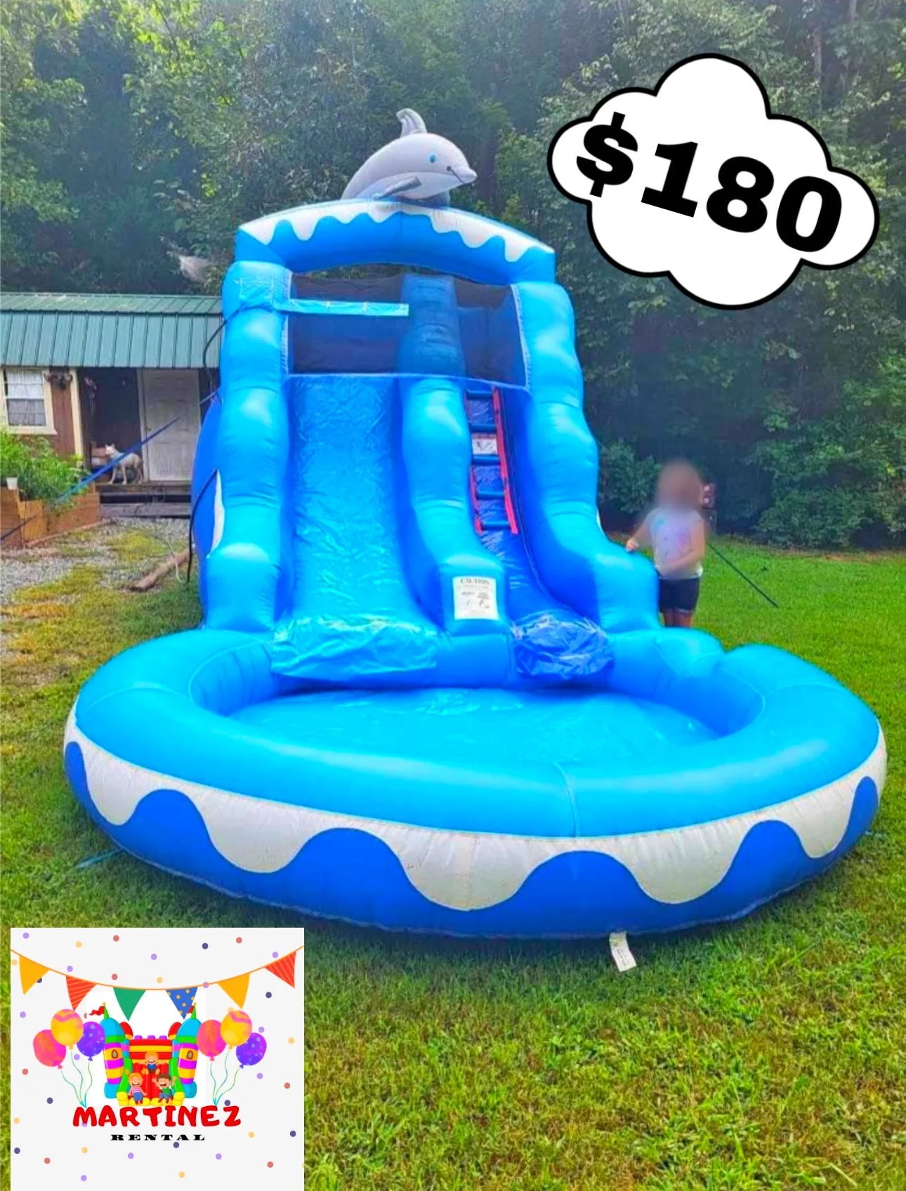 A large inflatable water slide in the shape of a dolphin, priced at $180, set up outdoors on grass with trees in the background. There is a small logo in the lower left corner for Martinez Rental, which features balloons and a festive theme.