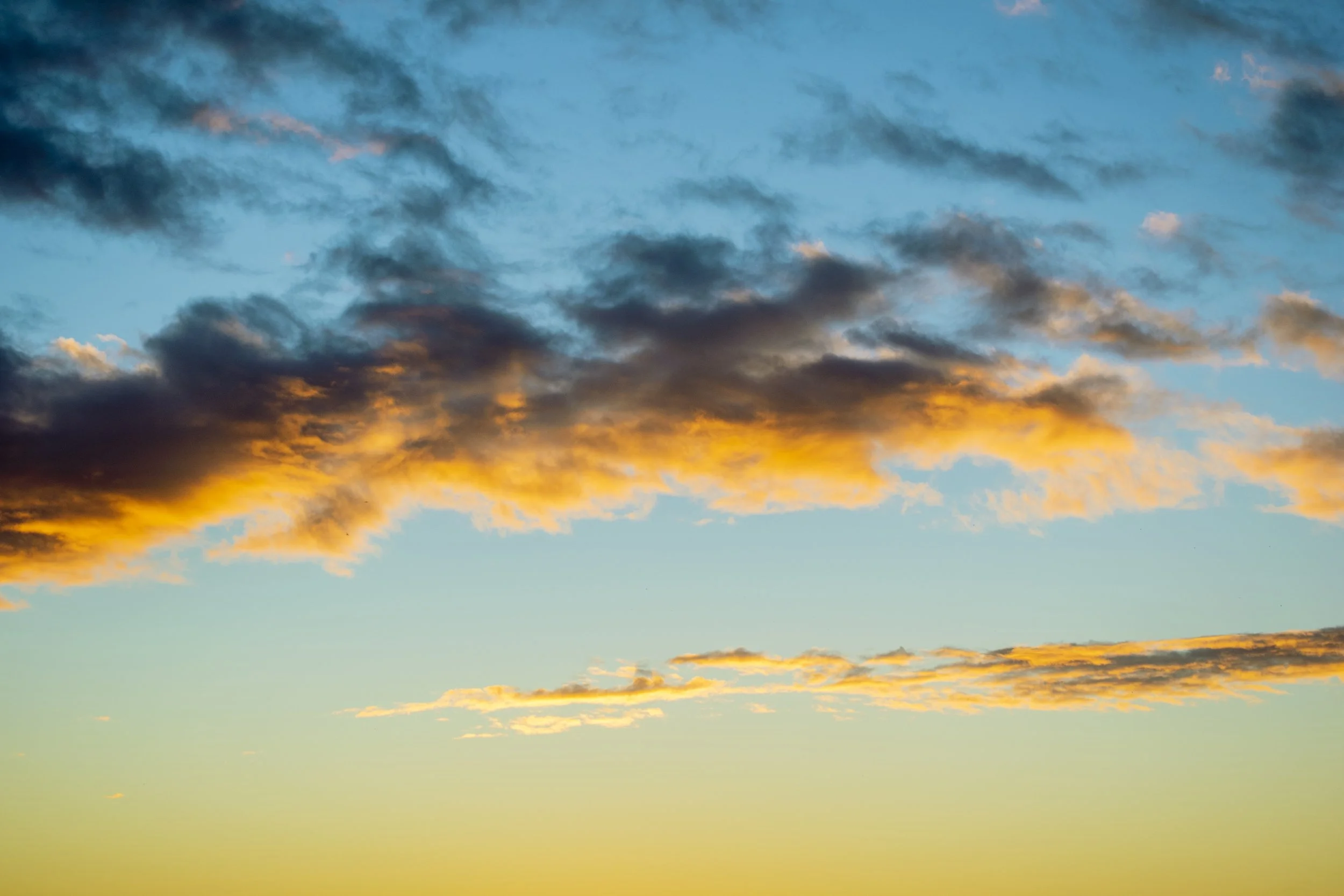 A sky filled with clouds during sunset or sunrise, with shades of orange and blue.
